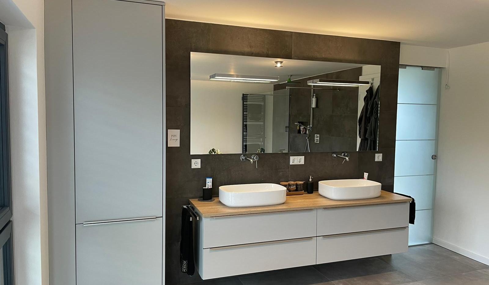 Modernes Badezimmer mit schwebendem Doppelwaschtisch, weißen Badmöbeln, Holzarbeitsplatte und großem Wandspiegel