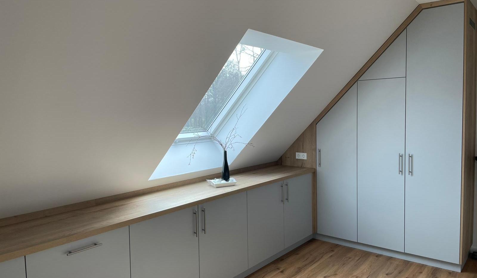 Maßgefertigter Einbauschrank unter der Dachschräge mit weißen Fronten und Holzdetails