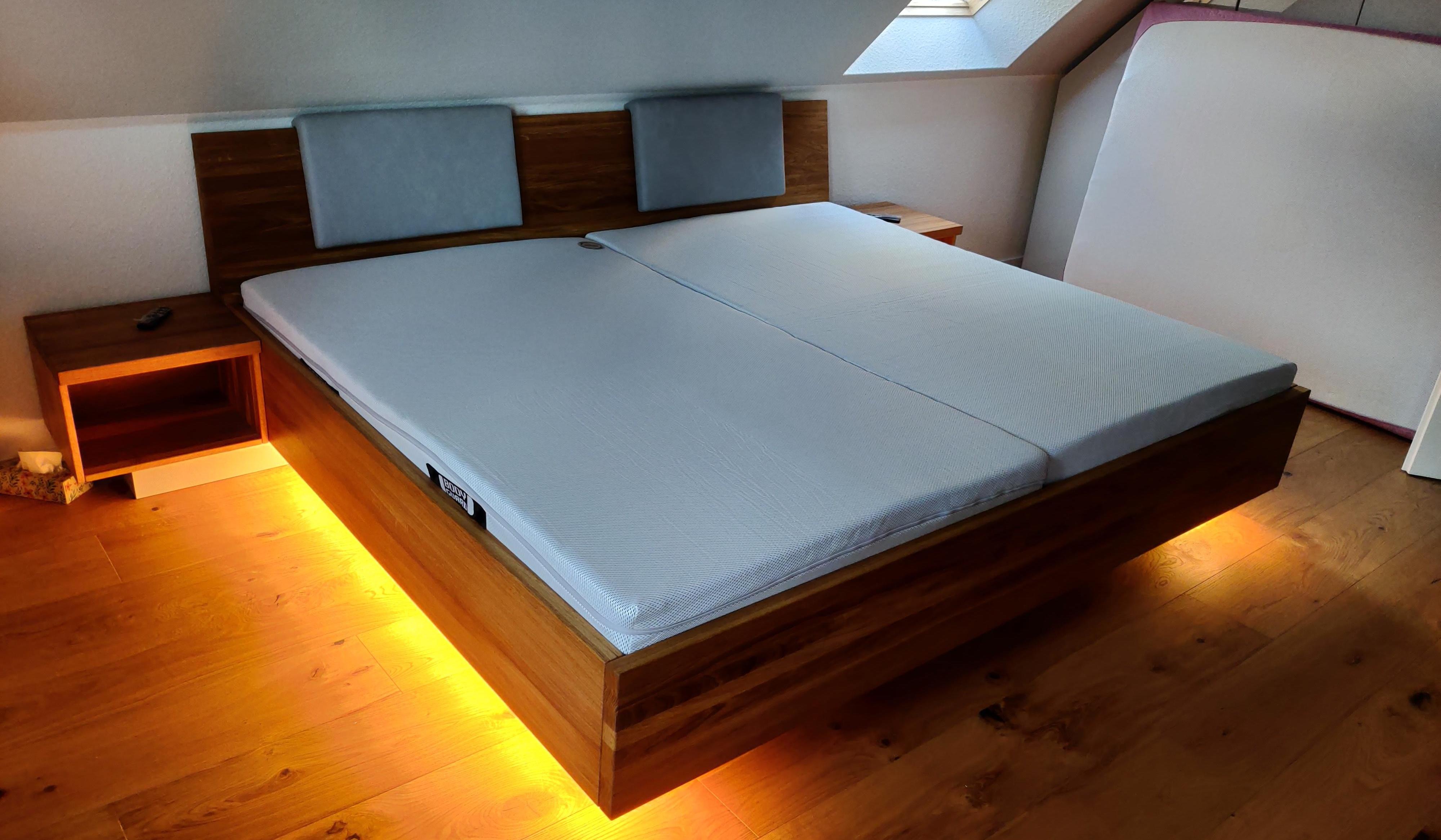 Maßgefertigtes Doppelbett aus Holz mit gepolstertem Kopfteil, Nachttischen und indirekter Beleuchtung unter der Dachschräge