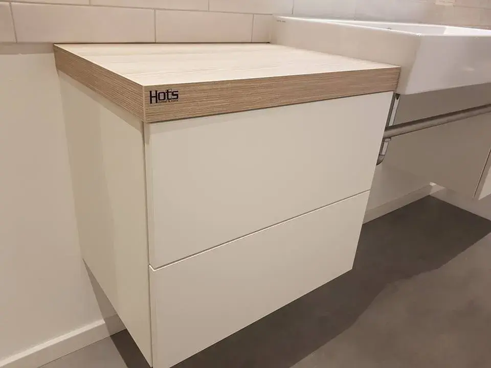 Moderner weißer Badschrank mit grifflosen Fronten, zwei Schubladen und Ablagefläche in heller Holzoptik