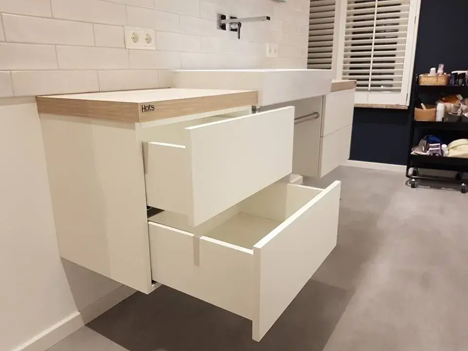 Weißer schwebender Waschtischunterschrank mit geöffneten Schubladen und moderner Waschtischanlage
