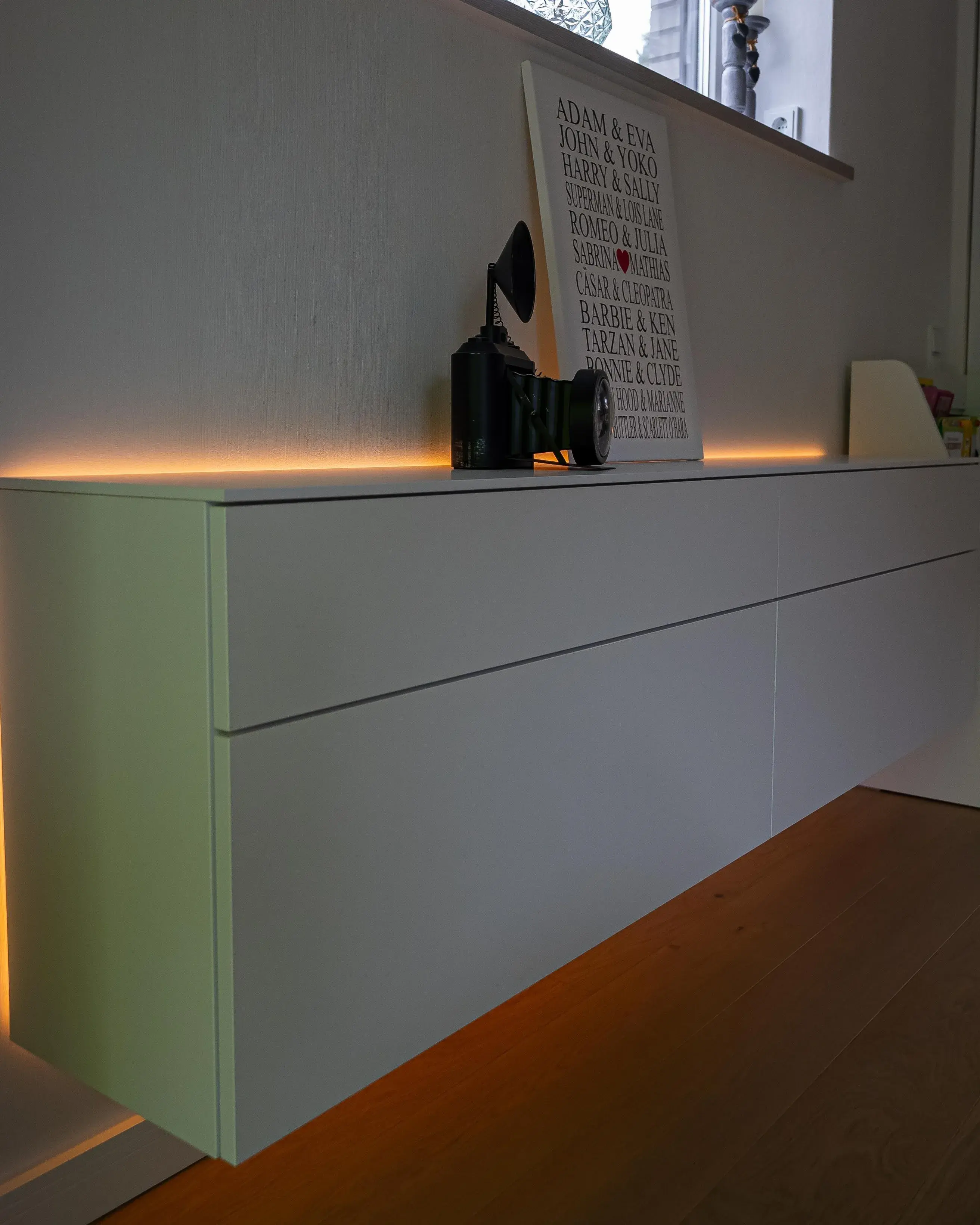 Modernes weißes Sideboard mit grifflosen Fronten und indirekter LED-Beleuchtung am Sockel