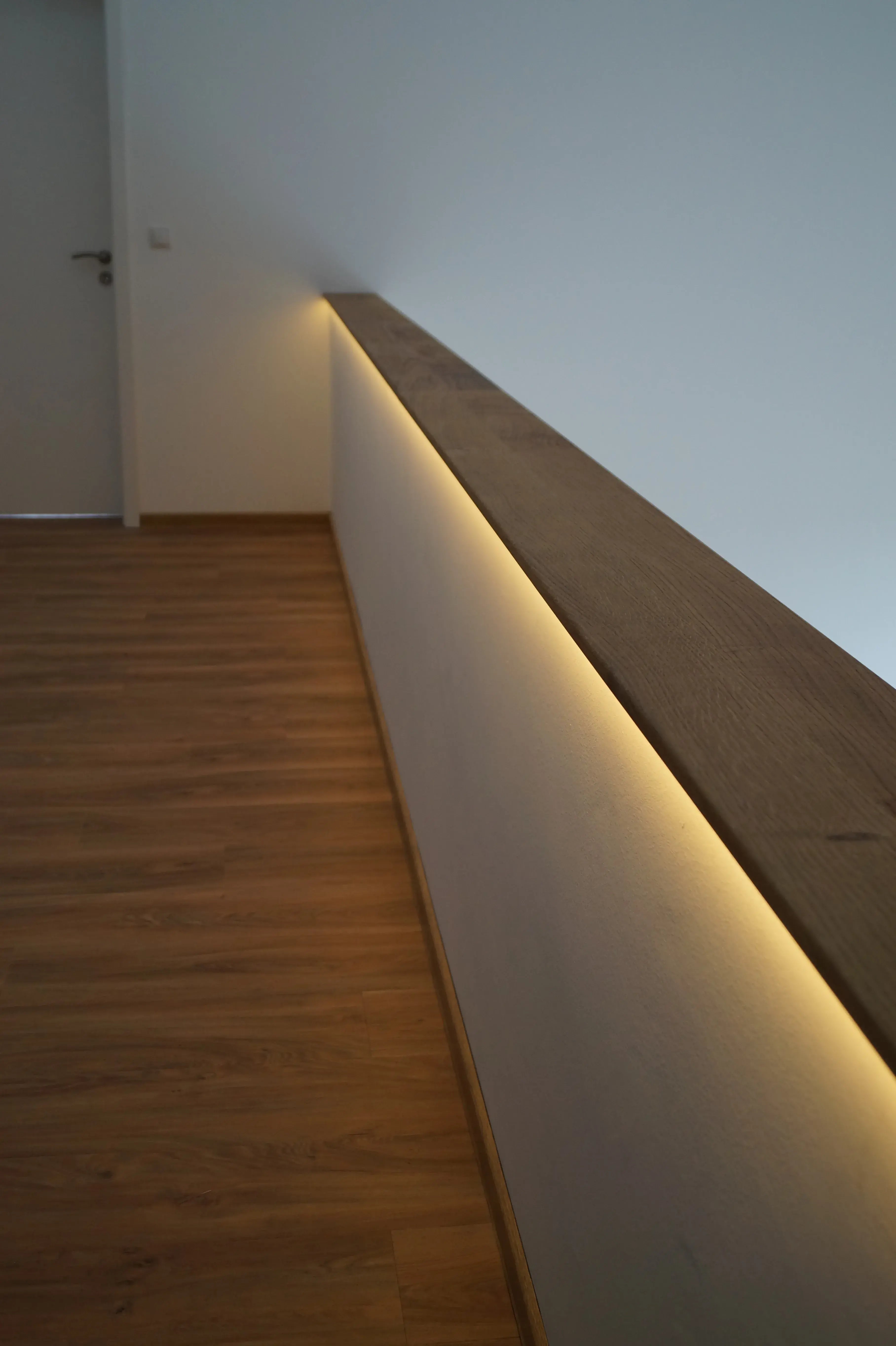 Holzhandlauf mit integrierter LED-Beleuchtung entlang des Treppenaufgangs
