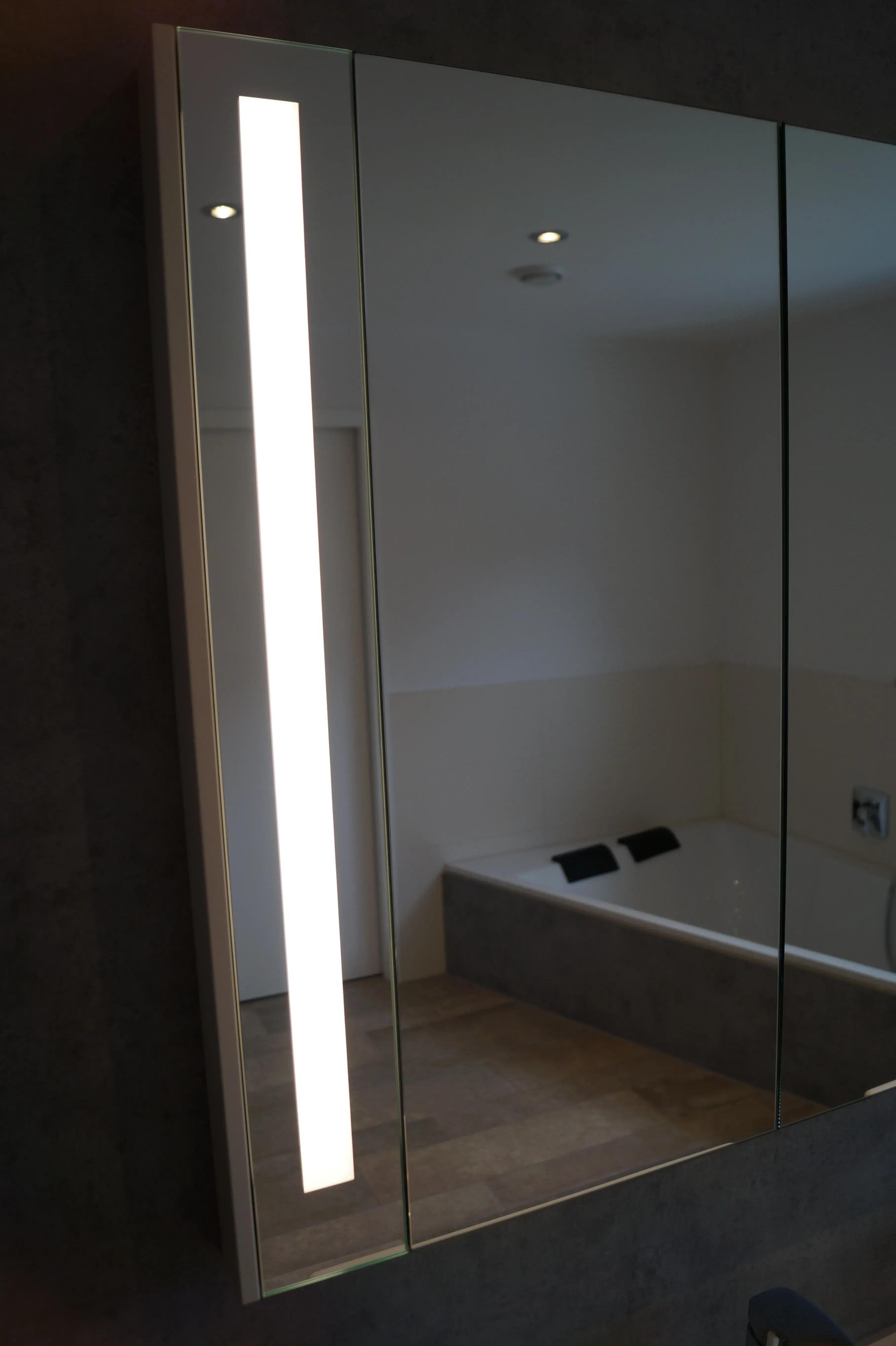 Moderner Badspiegel mit vertikal integrierter LED-Beleuchtung und Spiegelung der Badewanne