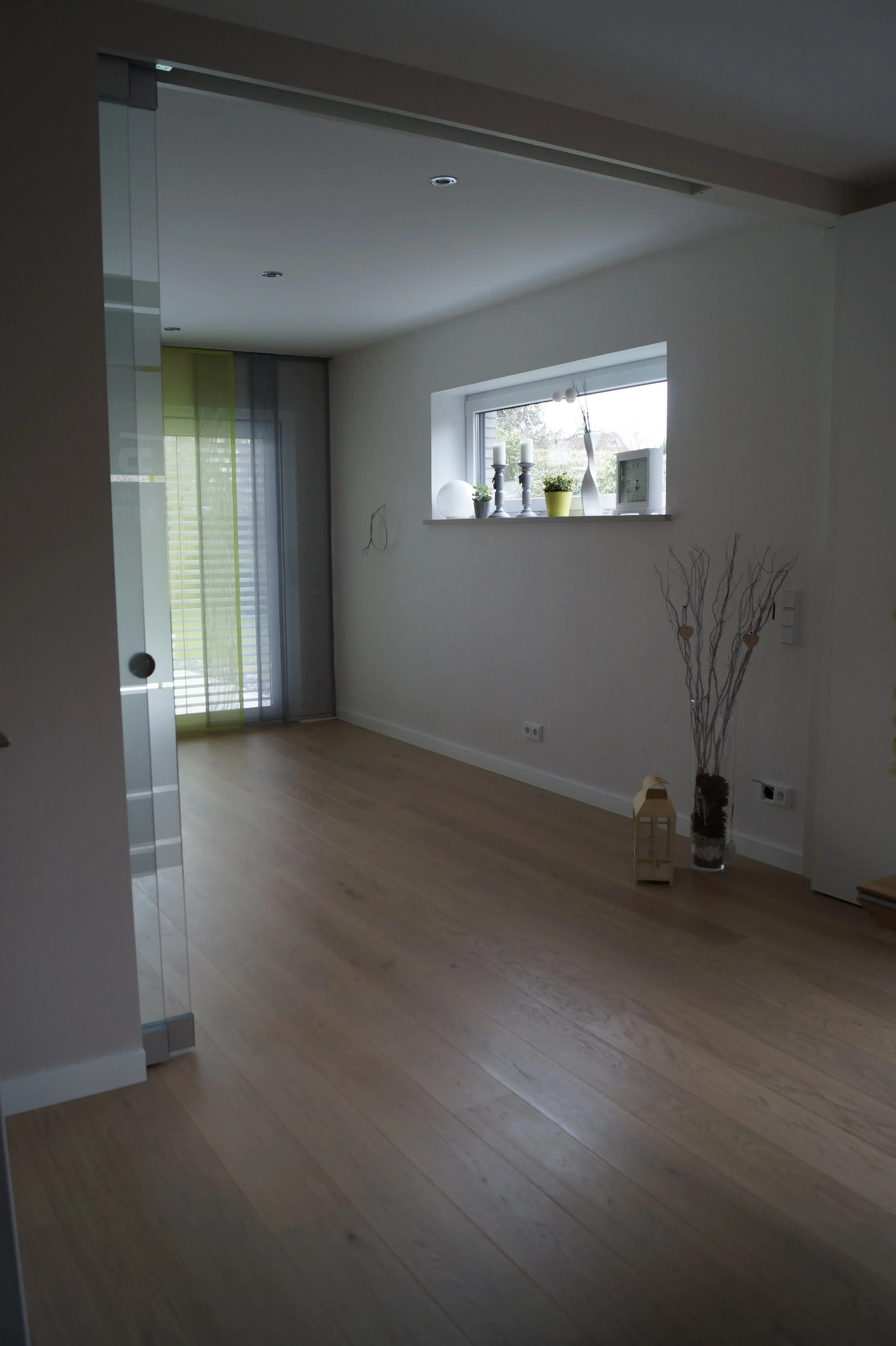 Heller Wohnraum mit Eichenholzboden, Glasschiebetür und bodentiefem Fenster