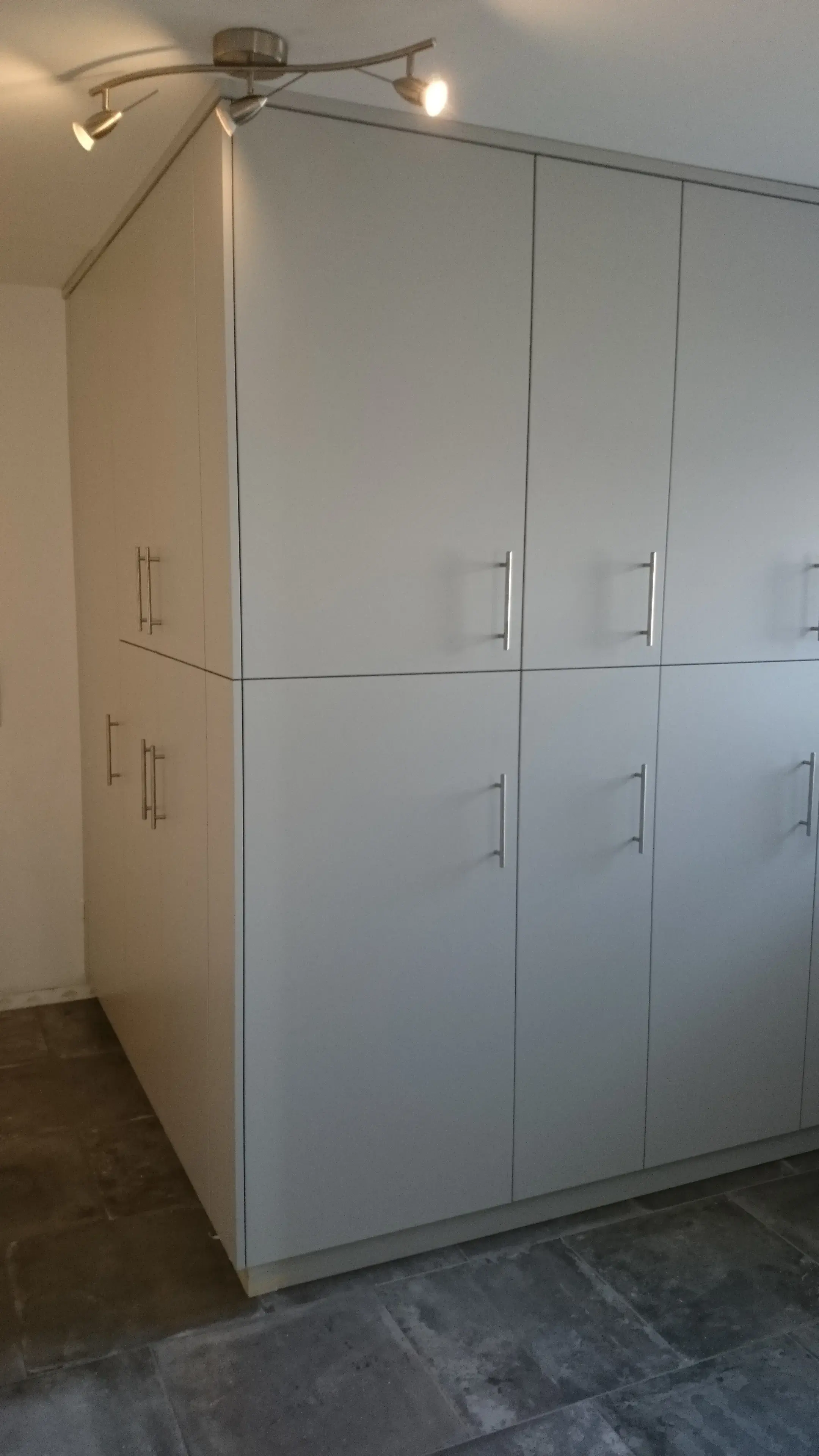 Maßgefertigter Hauswirtschaftsraum mit weißen deckenhohen Schränken und dunkler Arbeitsplatte