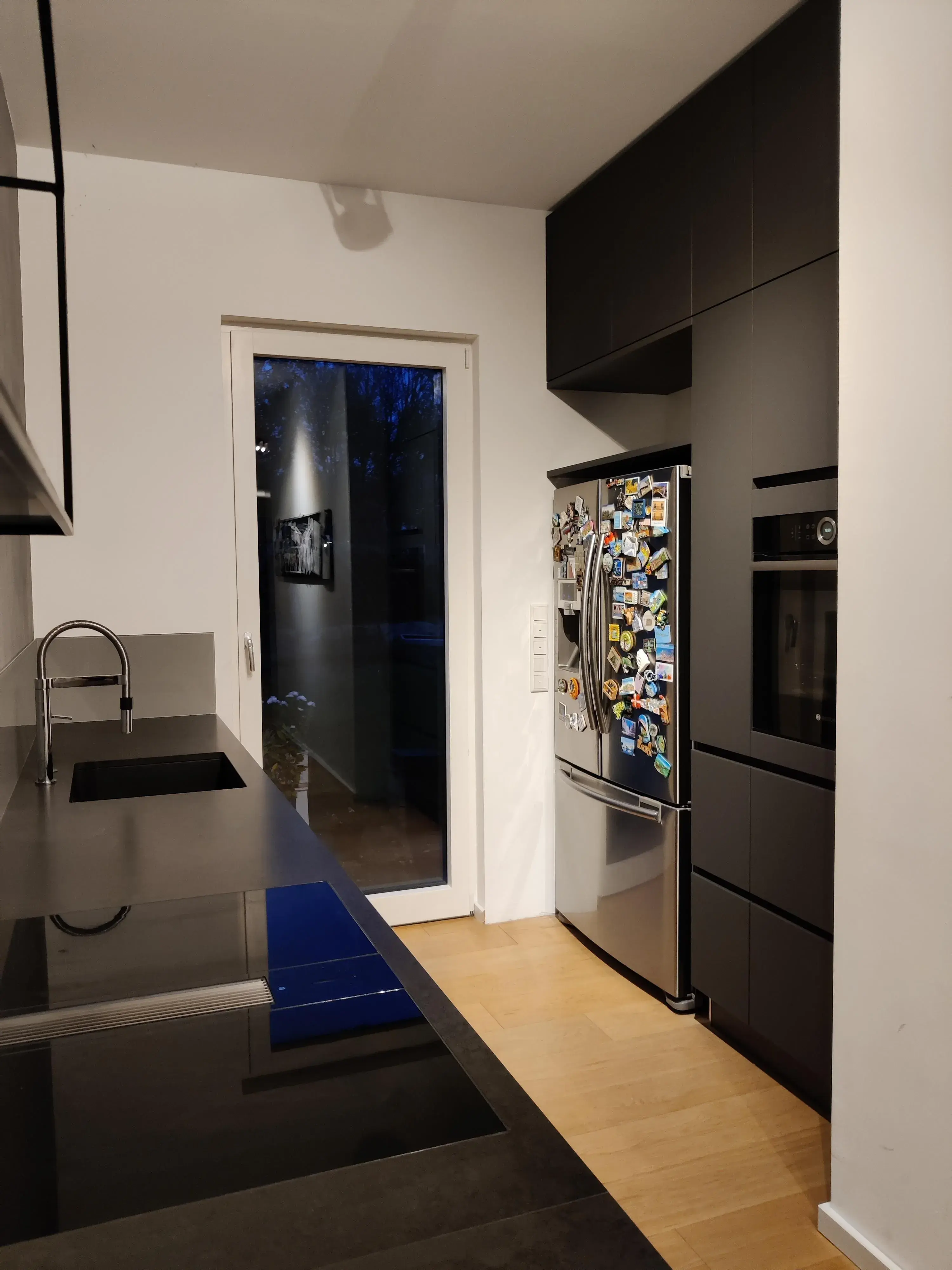 Moderne schwarze Küche mit Hochschränken, dunkler Arbeitsplatte und integriertem Kochfeld