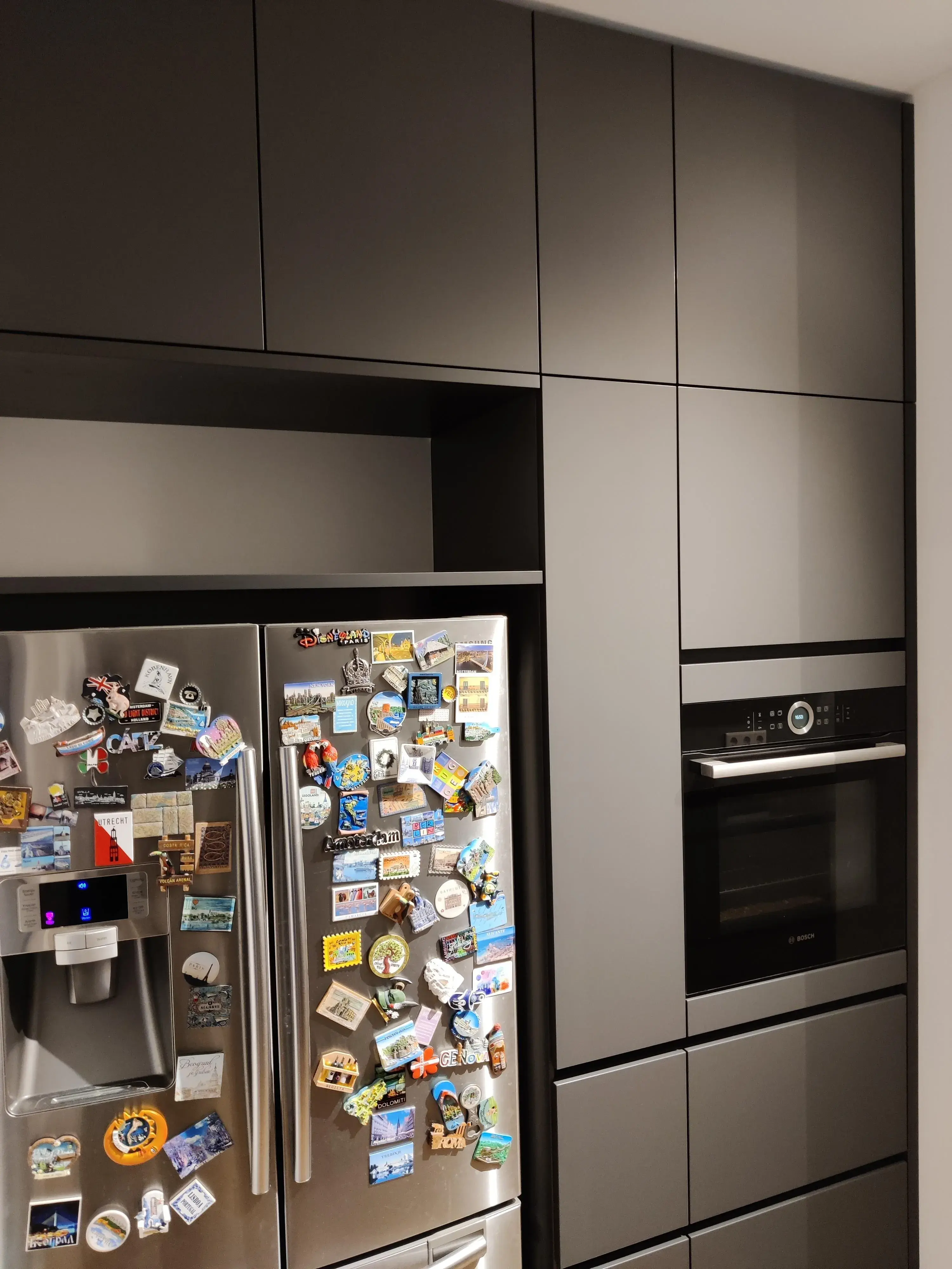 Anthrazitfarbene Hochschrankwand mit integriertem Backofen und Edelstahl-Kühlschrank in moderner KücheAnthrazitfarbene Hochschrankwand mit geöffnetem Apothekerschrank, Auszügen und integriertem Backofen