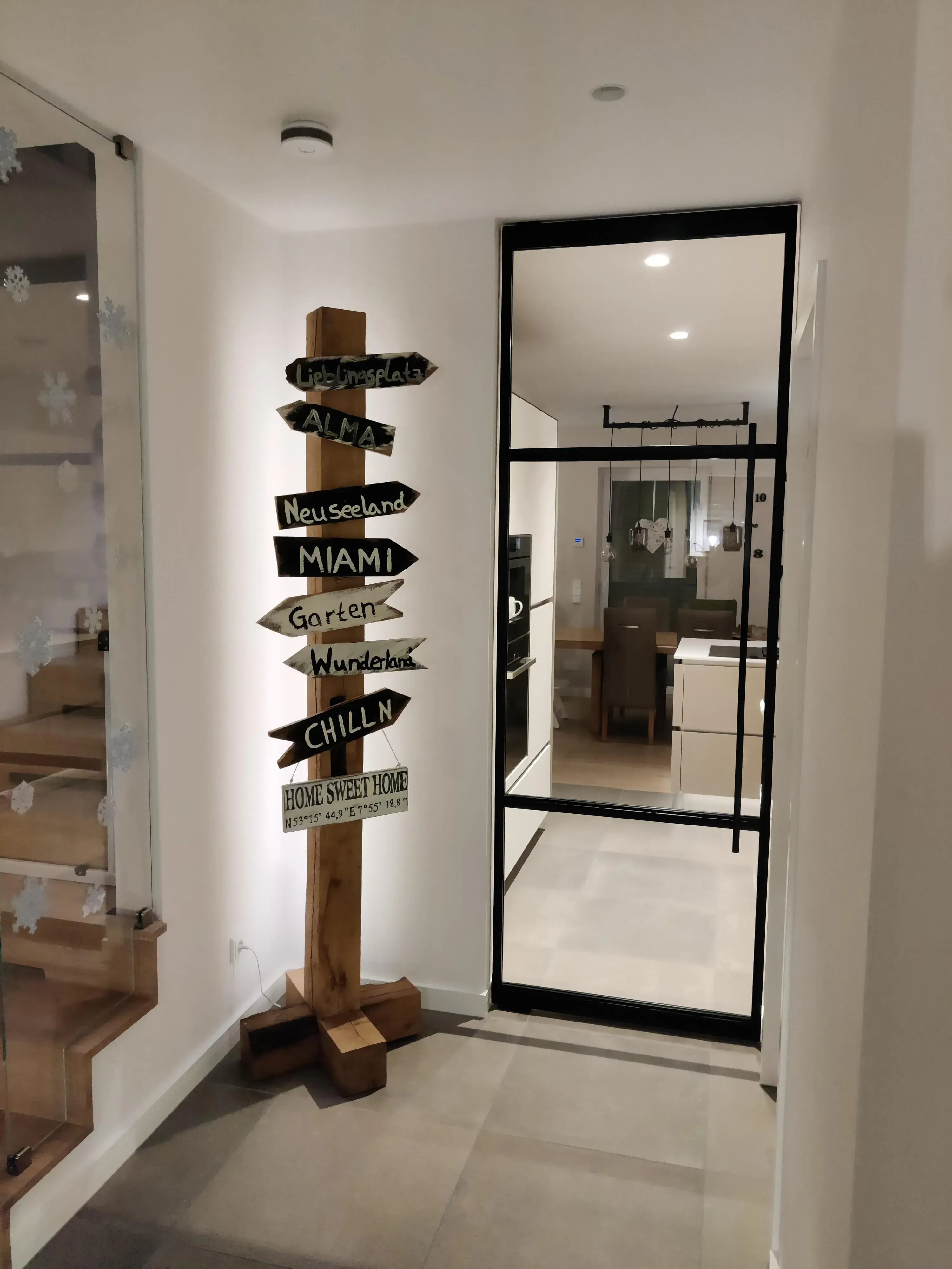 Moderner Flur mit schwarzer Loft-Glastür und Holztreppe