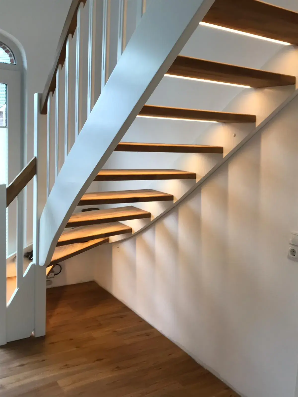 Offene Holztreppe mit weißem Geländer und integrierter LED-Beleuchtung