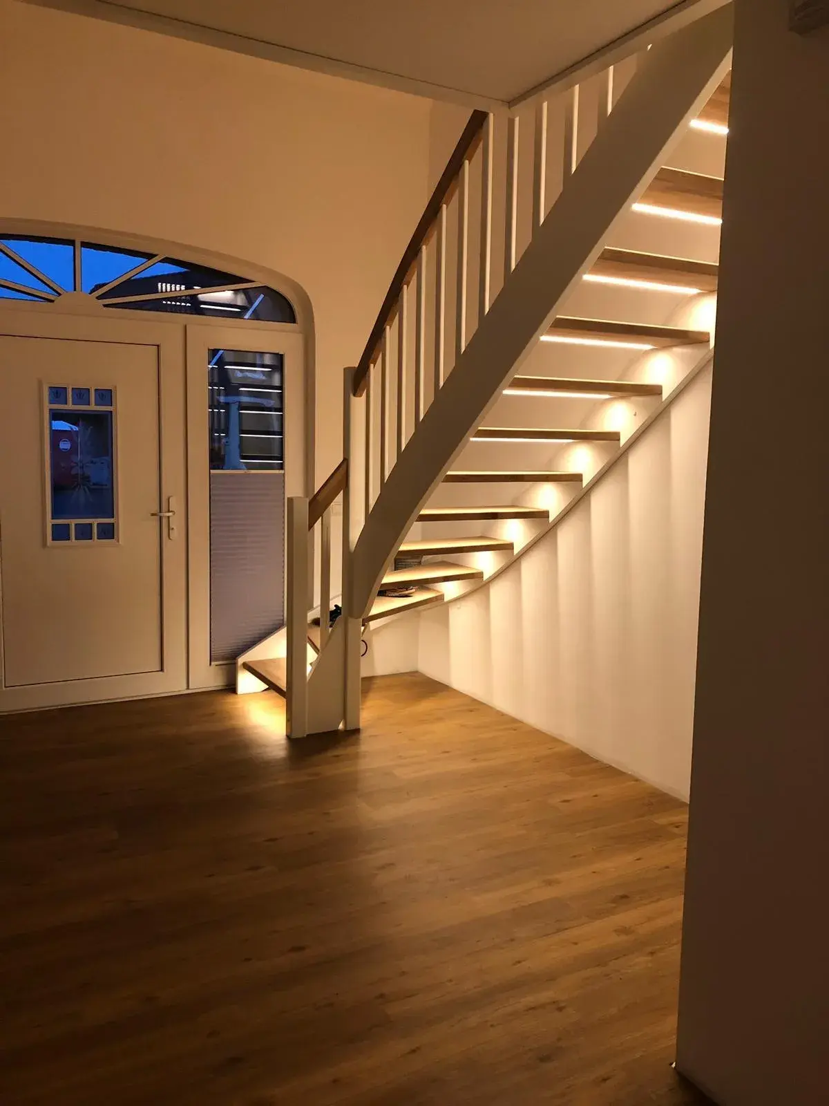 Maßgefertigte Holztreppe mit weißem Geländer und integrierter LED-Beleuchtung