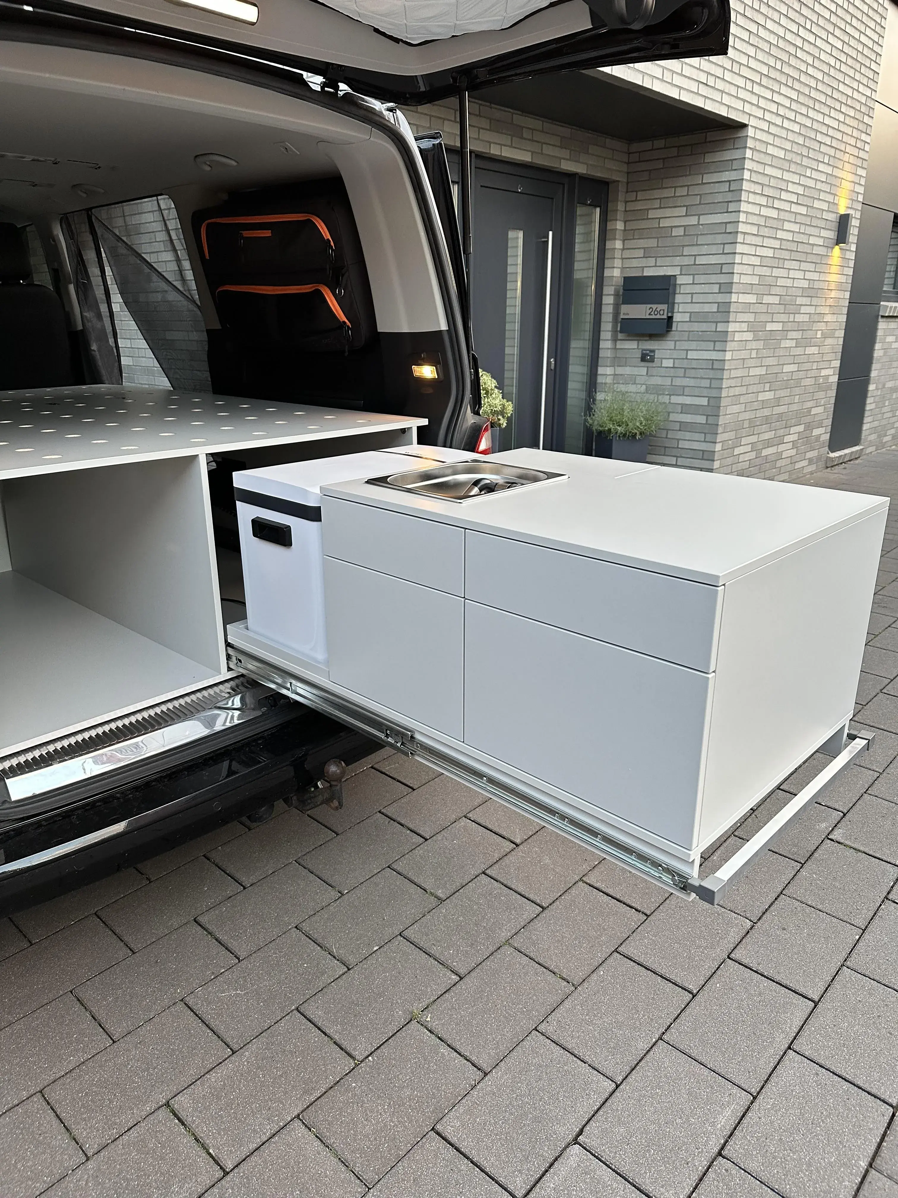 Ausziehbare Campingküche im Fahrzeugheck mit Spüle, Kühlbox, großer Arbeitsfläche und integriertem Stauraum