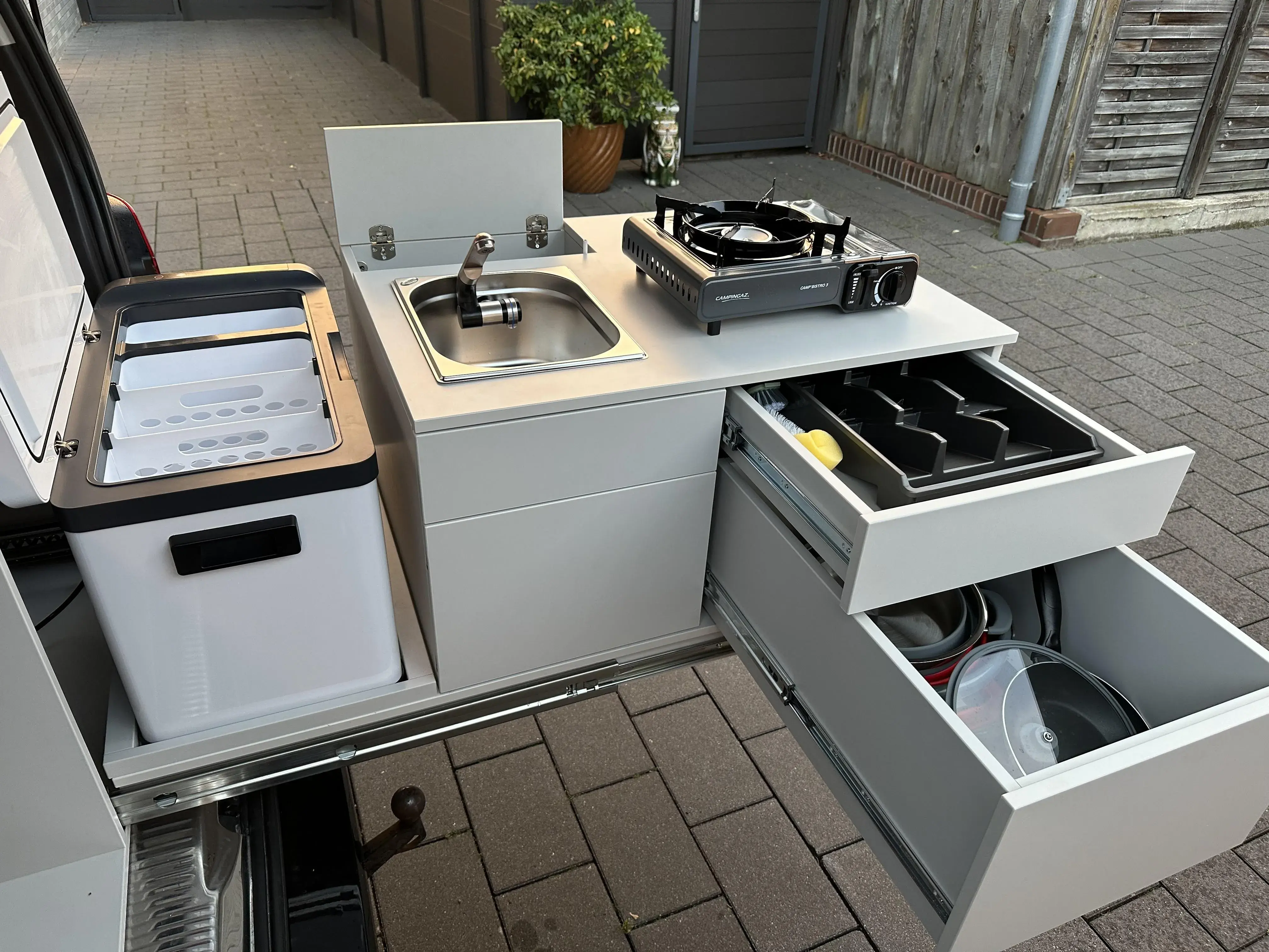 Ausziehbare Campingküche im Fahrzeugheck mit Kühlbox, Spüle, Gaskocher, Arbeitsfläche und geräumigen Schubladen