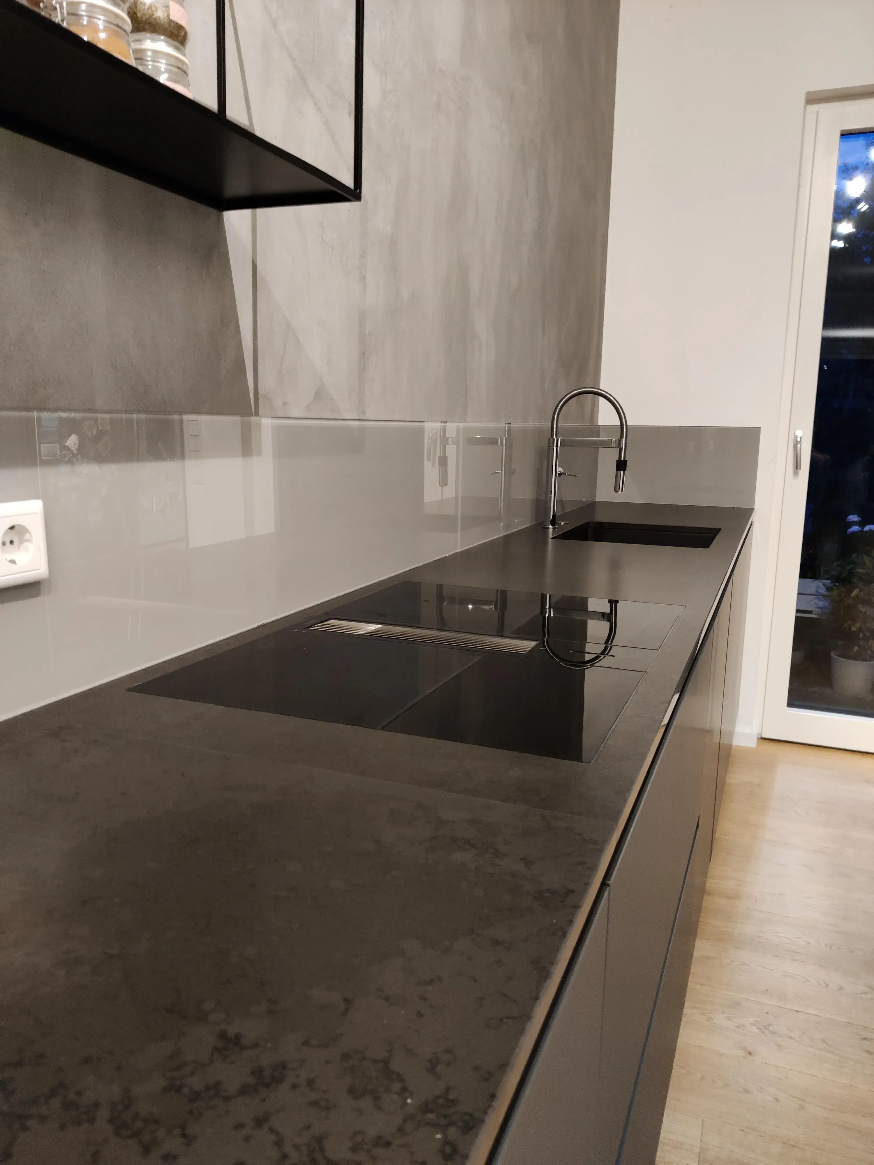 Moderne dunkle Küche mit Induktionskochfeld, integriertem Dunstabzug und schwarzer Spüle