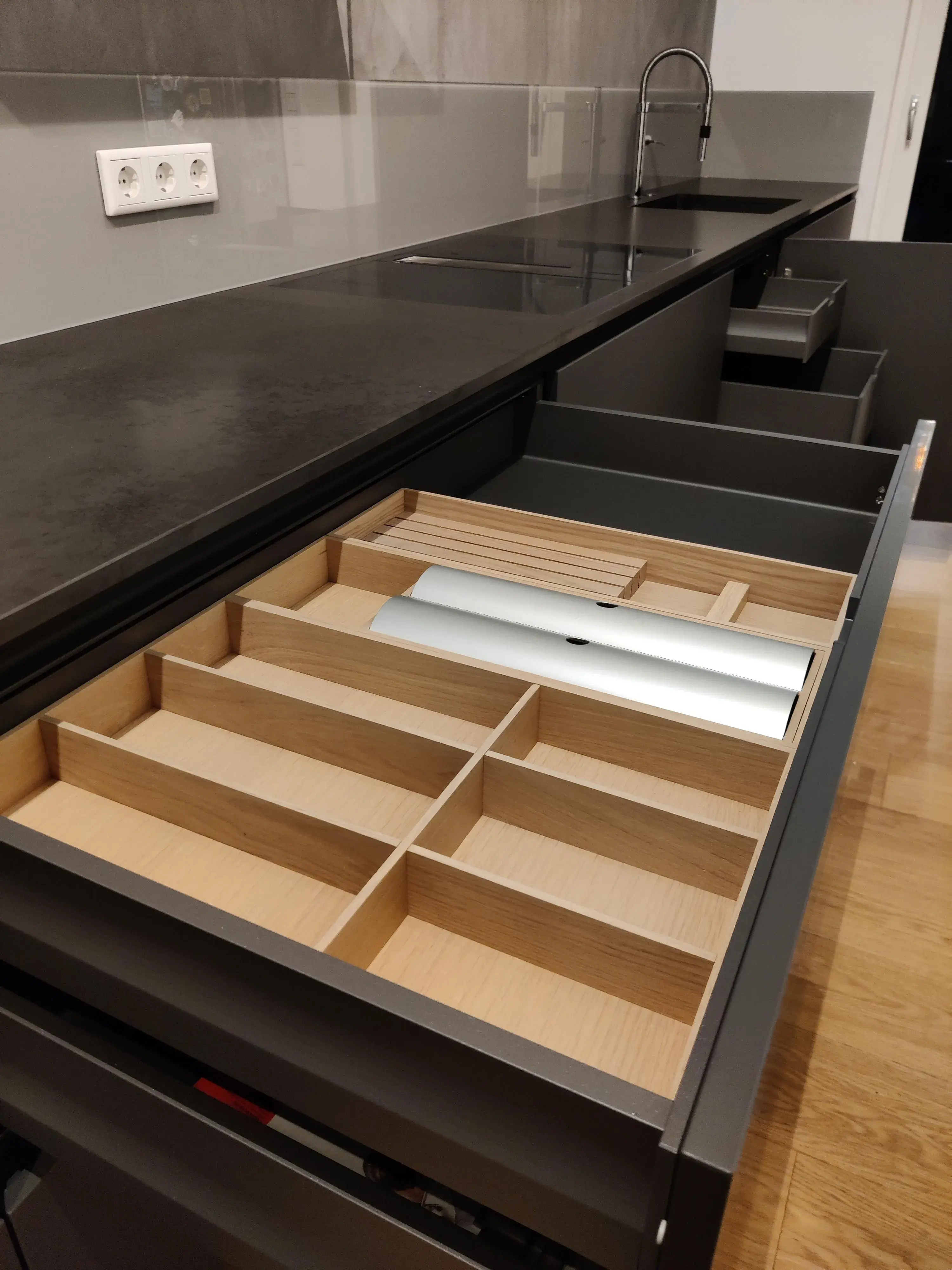 Geöffnete Küchenschublade mit hochwertigem Besteckeinsatz aus Holz und praktischem Stauraum