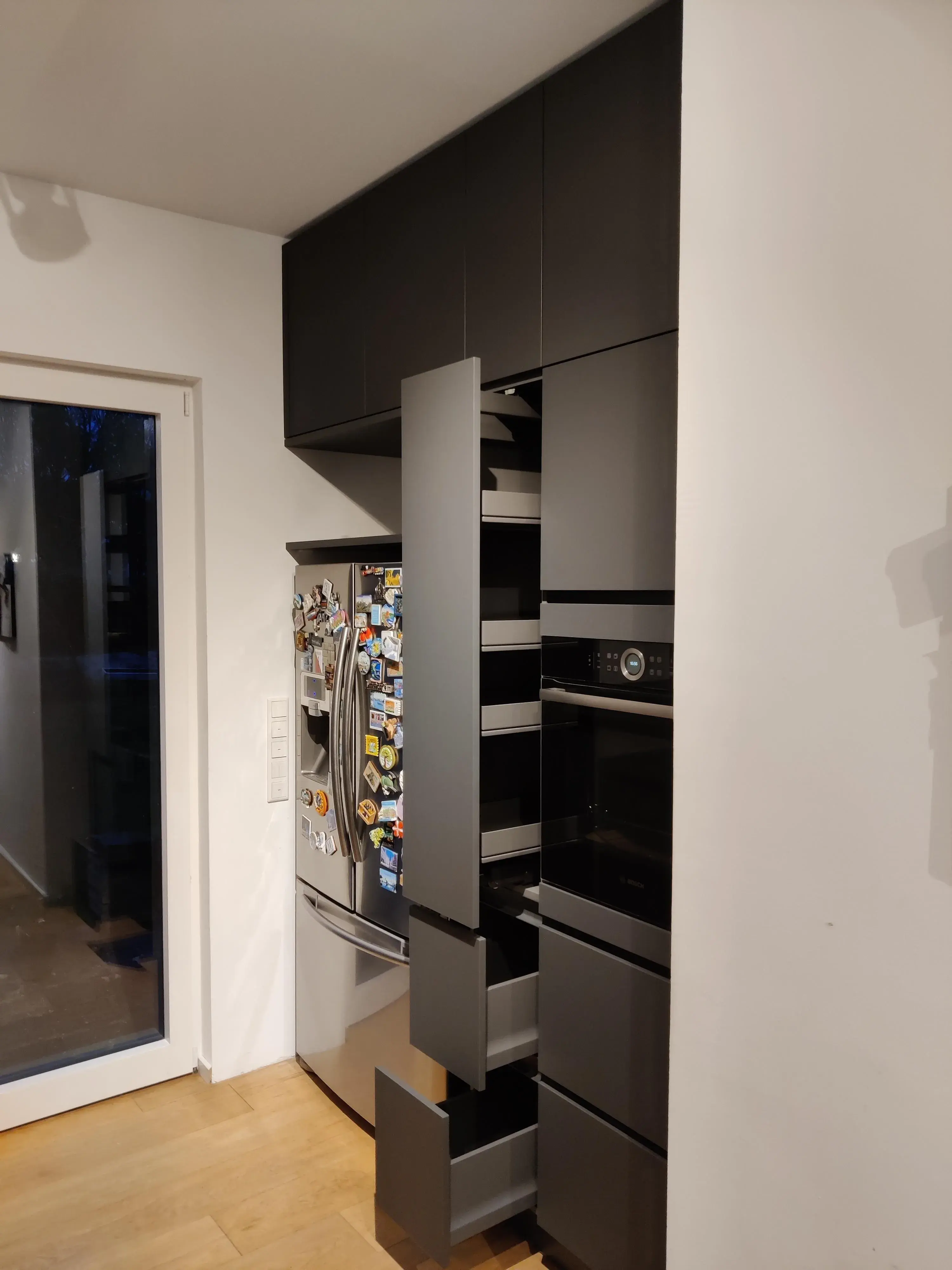 Anthrazitfarbene Hochschrankwand mit geöffnetem Apothekerschrank, Auszügen und integriertem Backofen