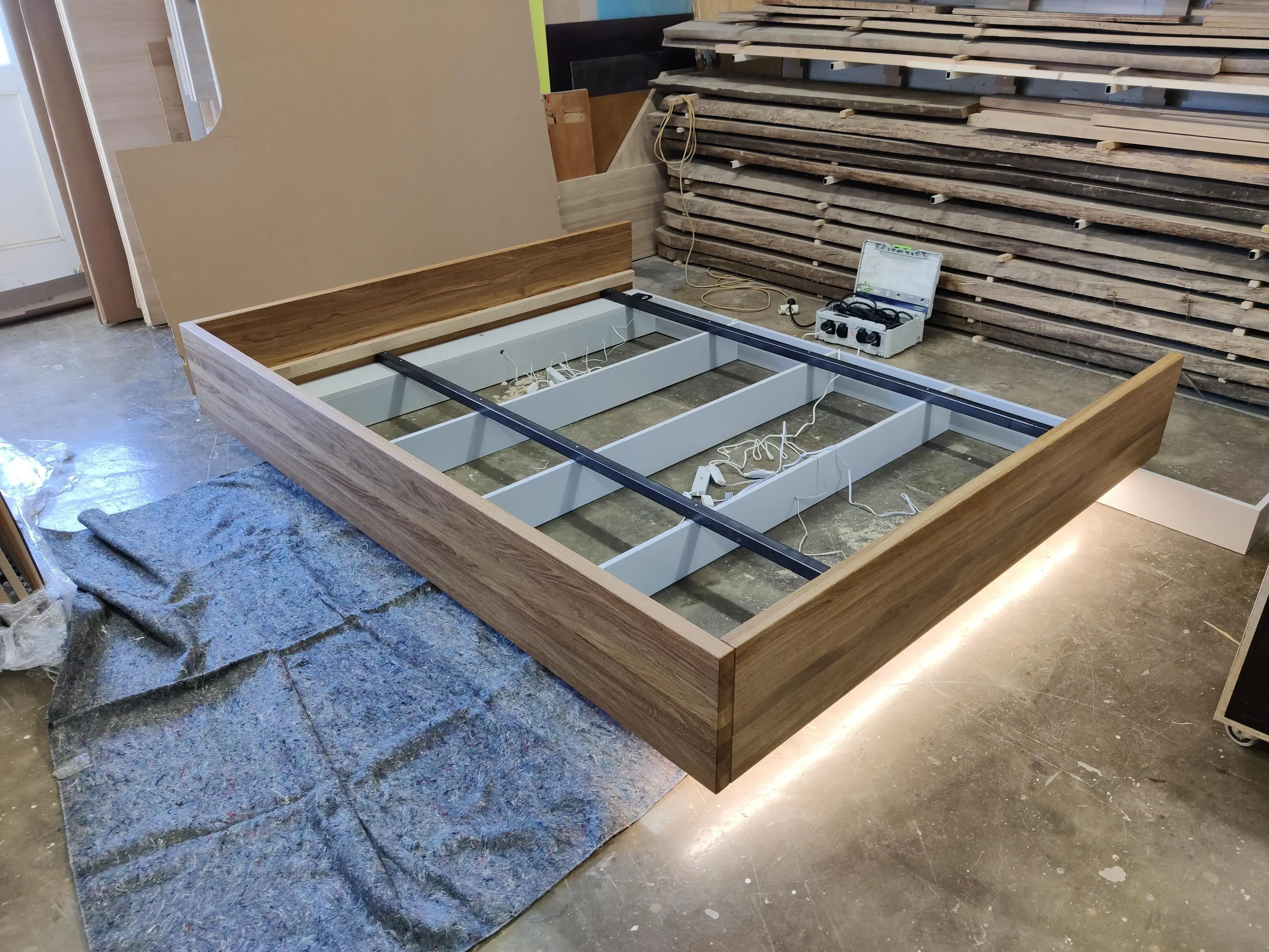 Maßgefertigtes Doppelbett aus Holz mit integrierter LED-Beleuchtung während der Fertigung in der Tischlerei