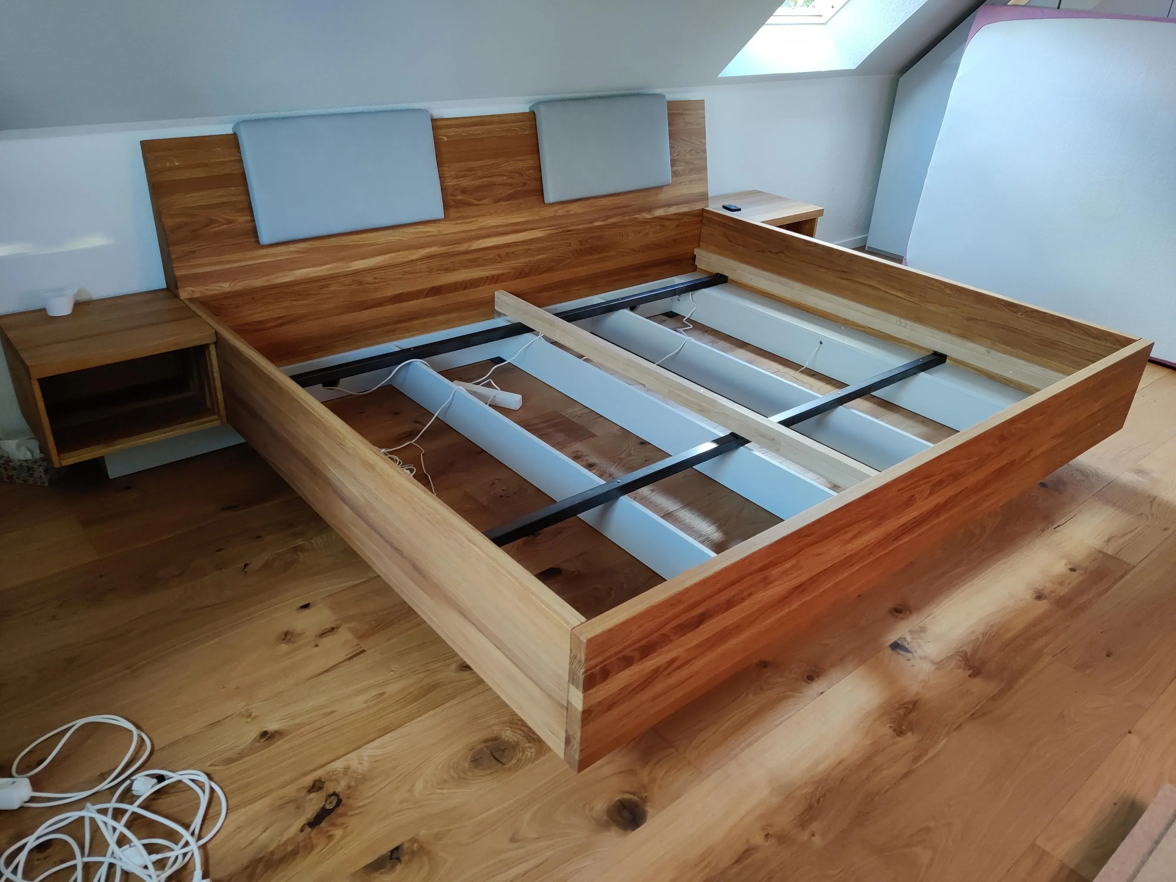 Maßgefertigtes Doppelbett aus Holz mit stabilem Unterbau, gepolstertem Kopfteil und integrierten Nachttischen