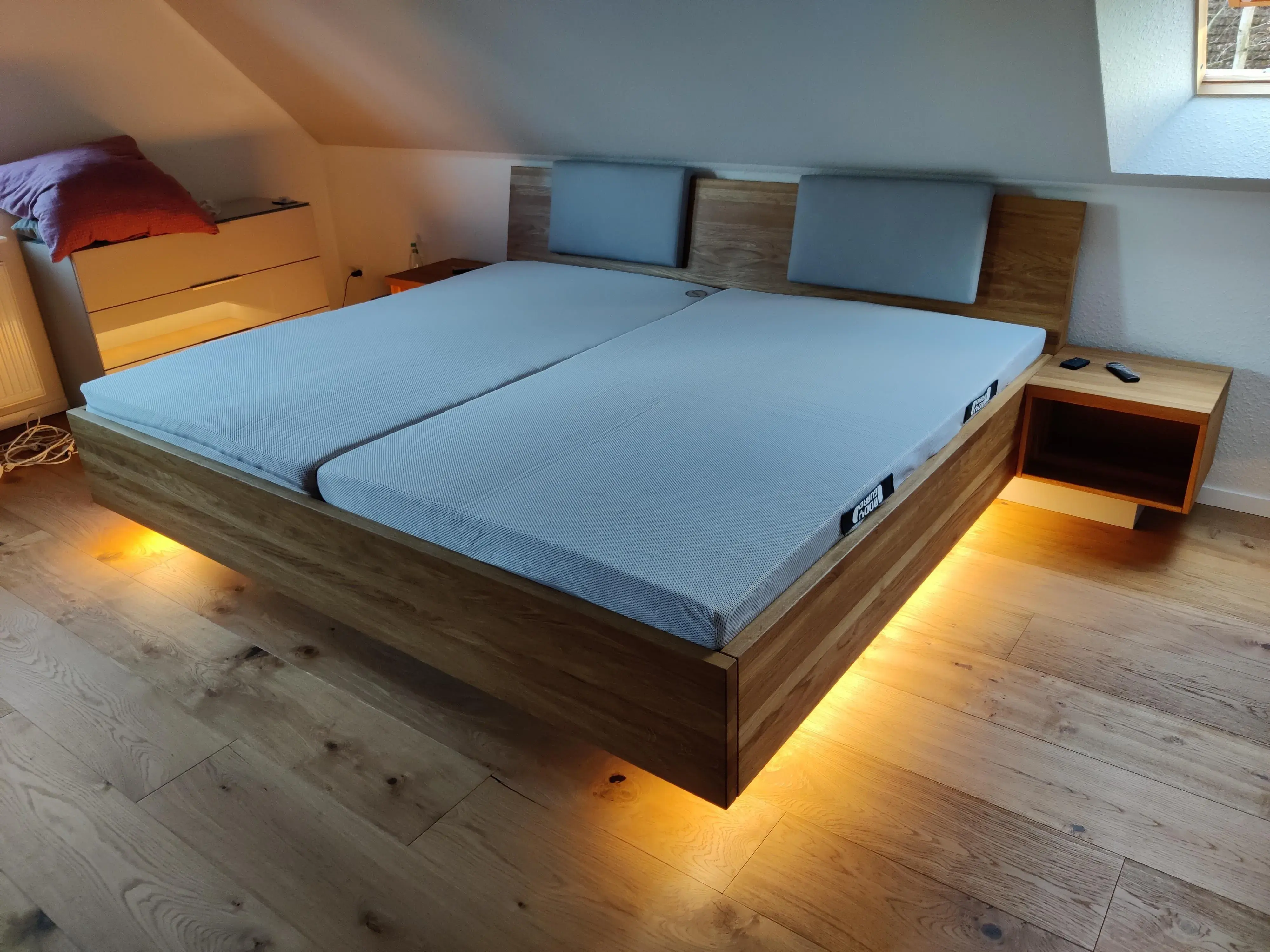 Maßgefertigtes Doppelbett aus Holz mit gepolstertem Kopfteil, schwebenden Nachttischen und indirekter Beleuchtung
