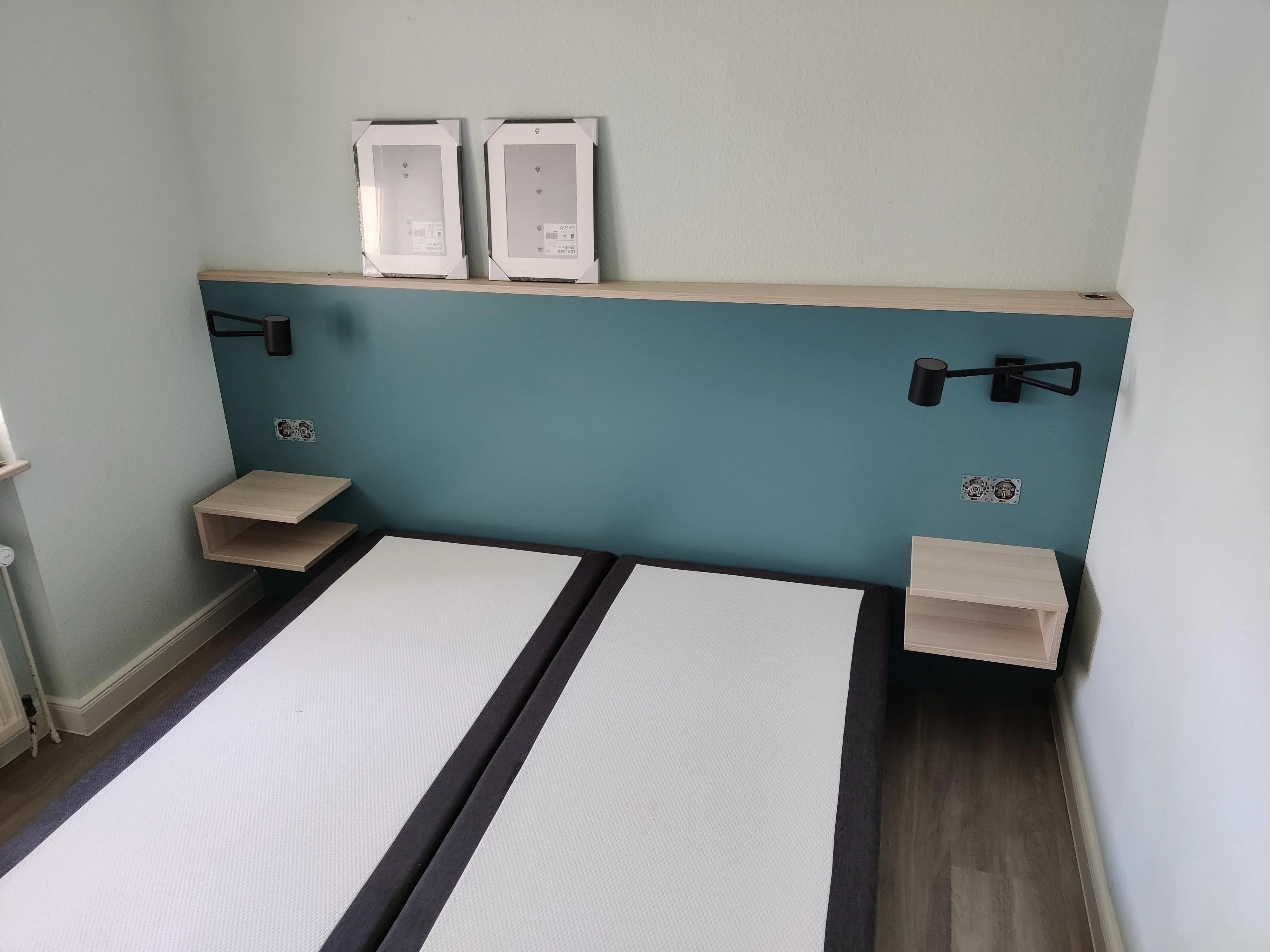 Maßgefertigtes Doppelbett mit türkisfarbenem Kopfteil, integrierten Leselampen und schwebenden Nachttischen