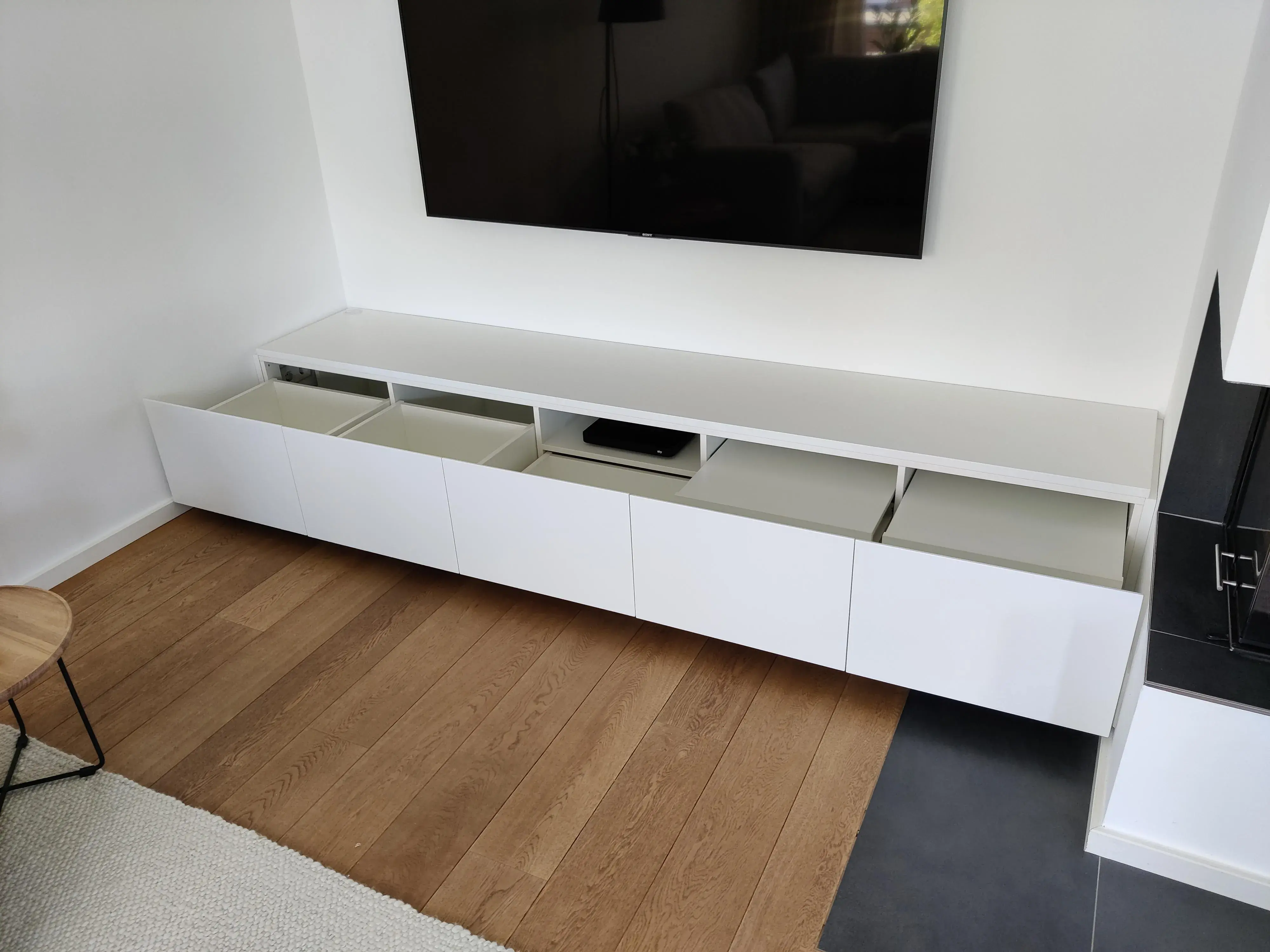 Maßgefertigtes weißes TV-Lowboard mit geöffneten Fronten und integriertem Stauraum im Wohnzimmer
