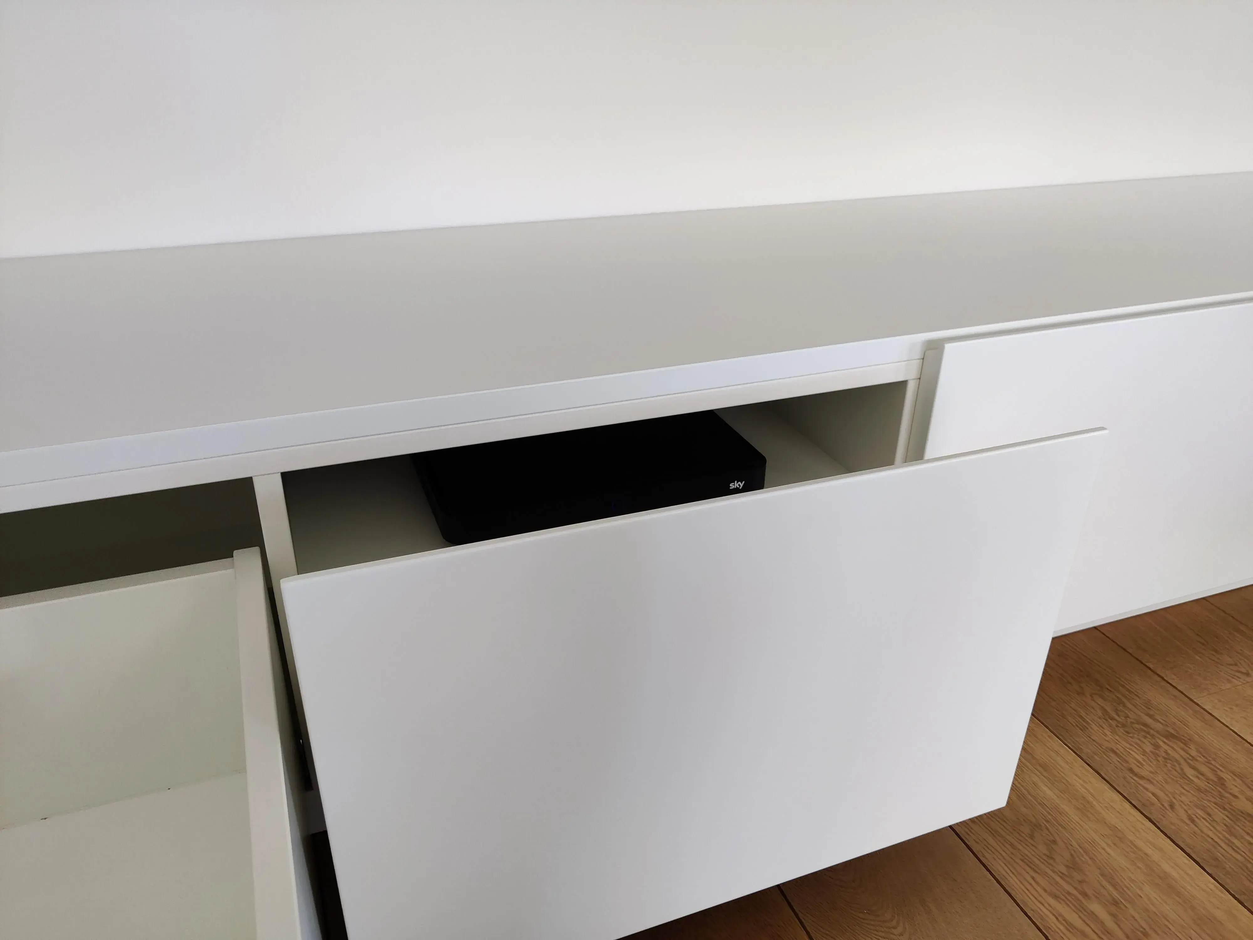 Maßgefertigtes weißes Sideboard mit geöffneten Fronten und integriertem Stauraum für Technik