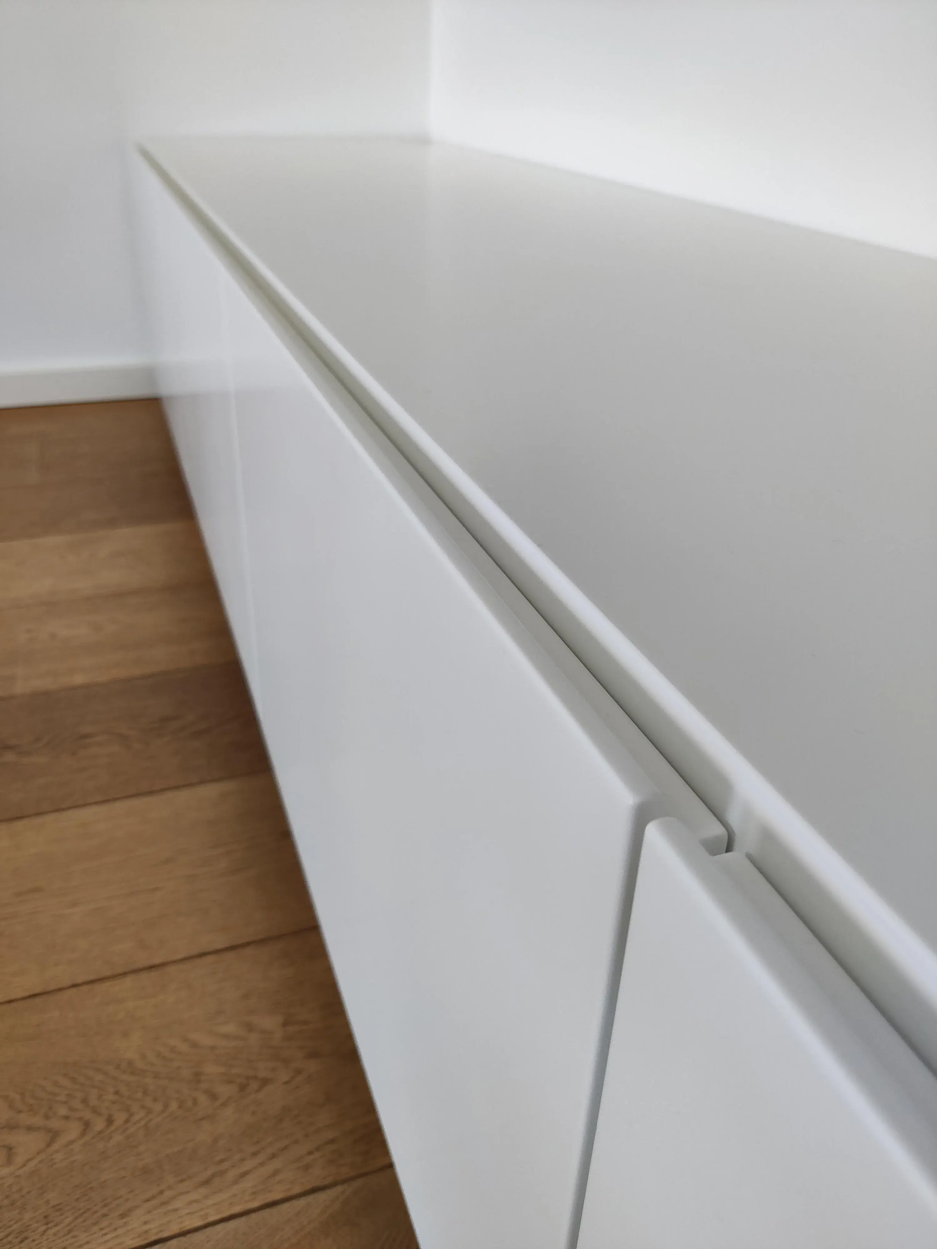Detailansicht eines maßgefertigten weißen Sideboards mit grifflosen Fronten und flächenbündigem Design