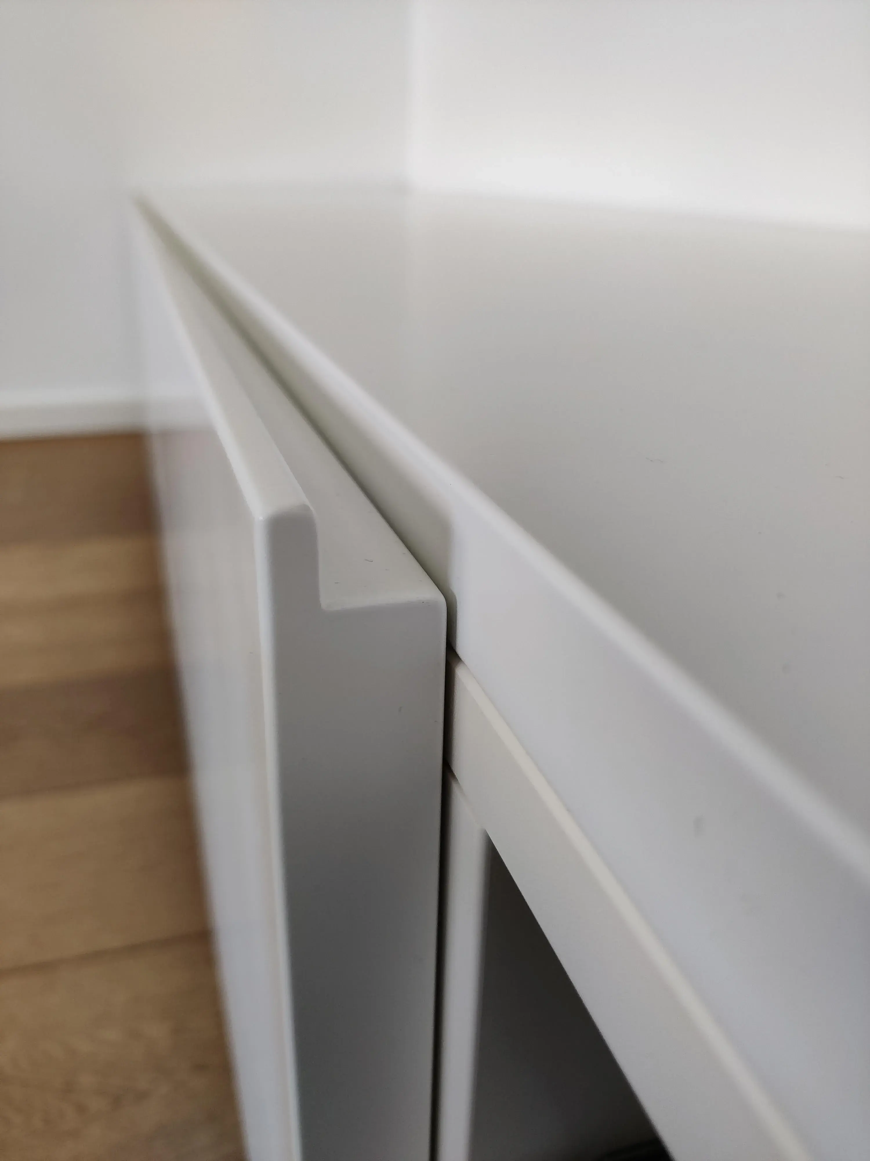 Detailaufnahme eines maßgefertigten weißen Sideboards mit griffloser Front und präziser Kantenverarbeitung