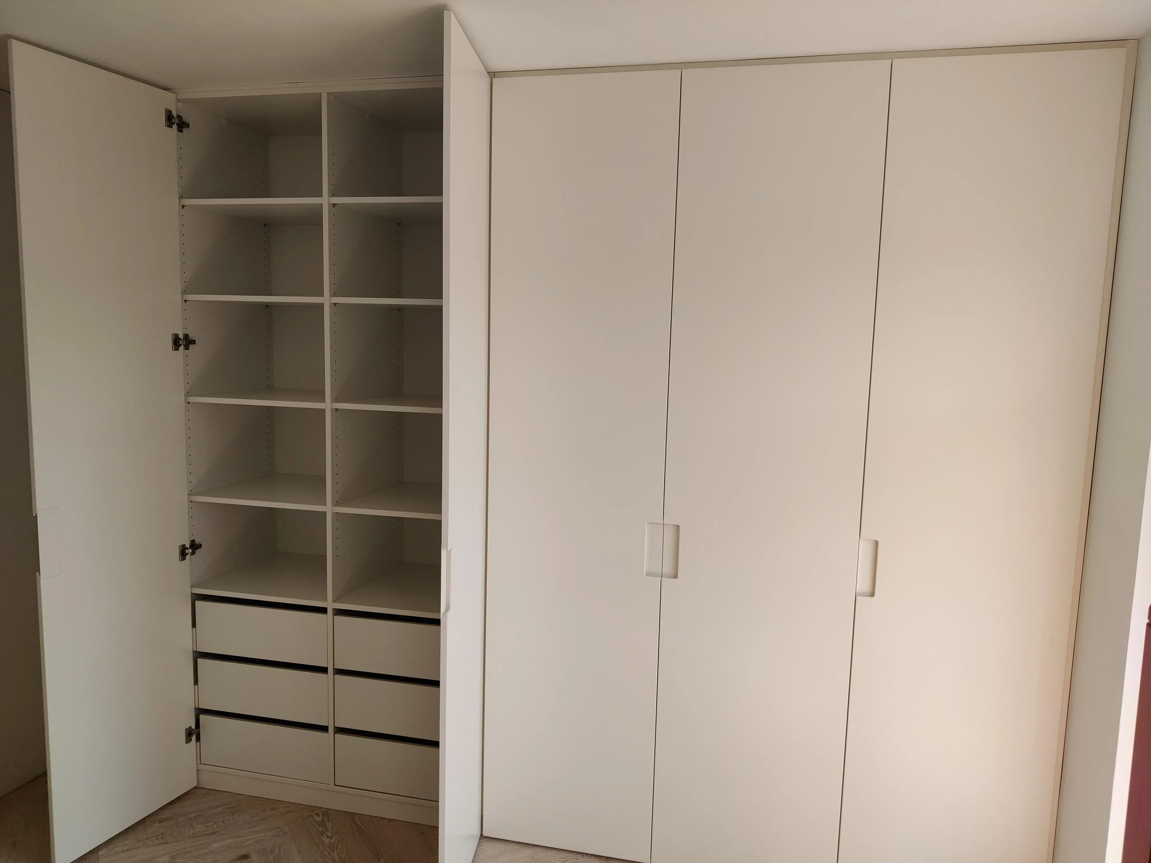 Geöffneter maßgefertigter Einbauschrank in Weiß mit Regalböden und Schubladen