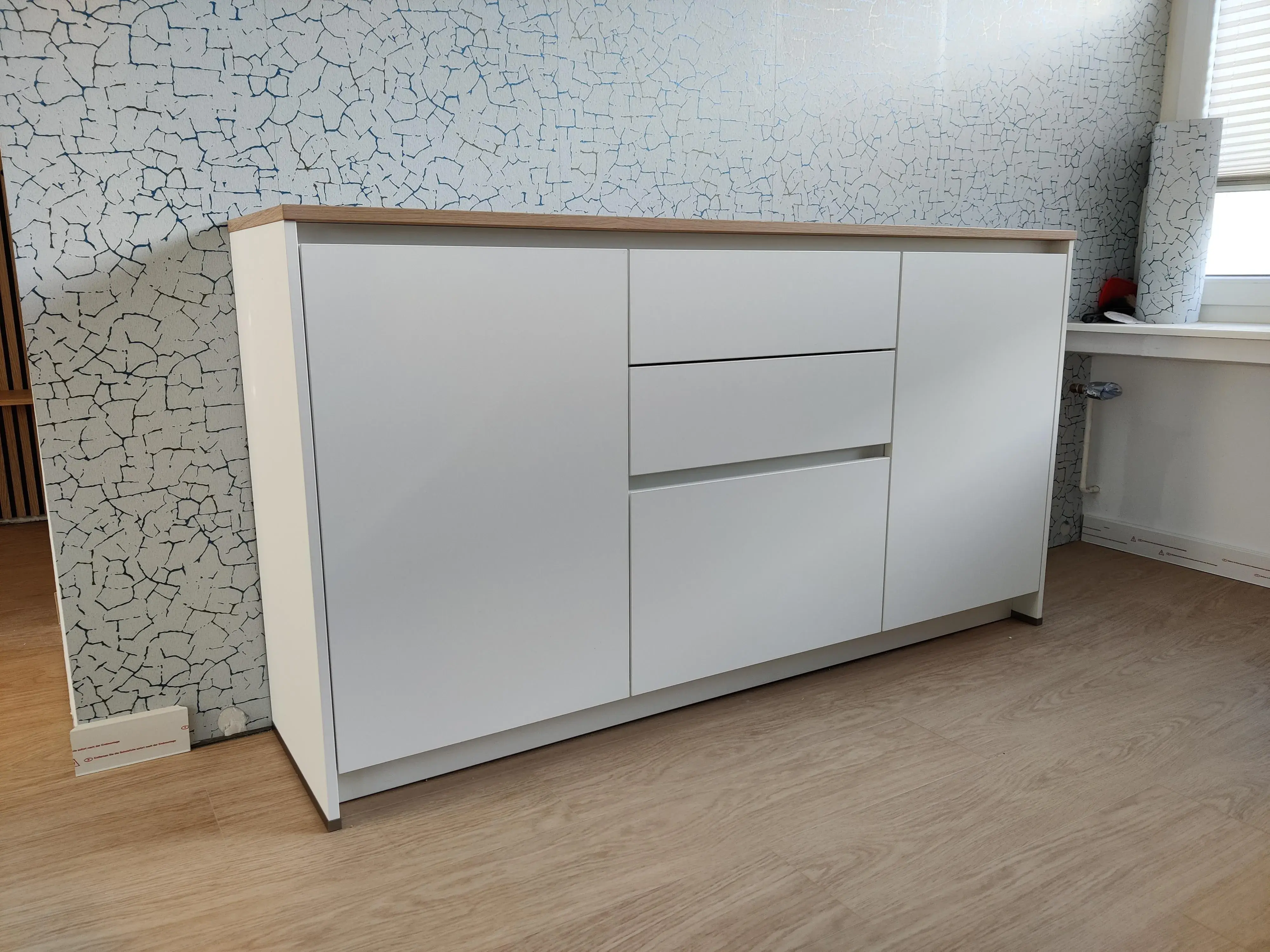 Modernes weißes Sideboard mit grifflosen Fronten und Abdeckplatte in Holzoptik