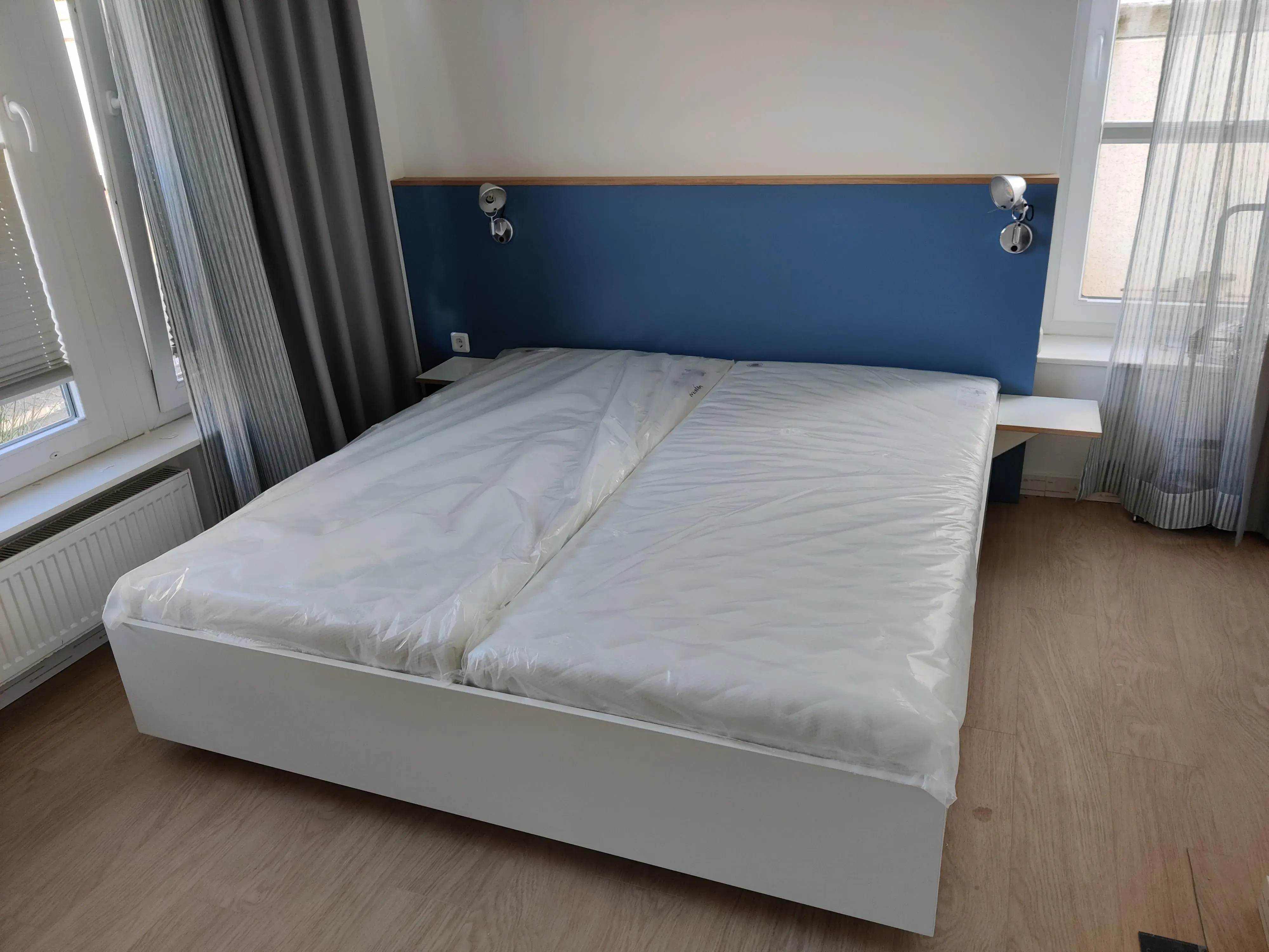 Maßgefertigtes Doppelbett mit blauem Kopfteil, integrierten Leselampen und seitlichen Ablagen