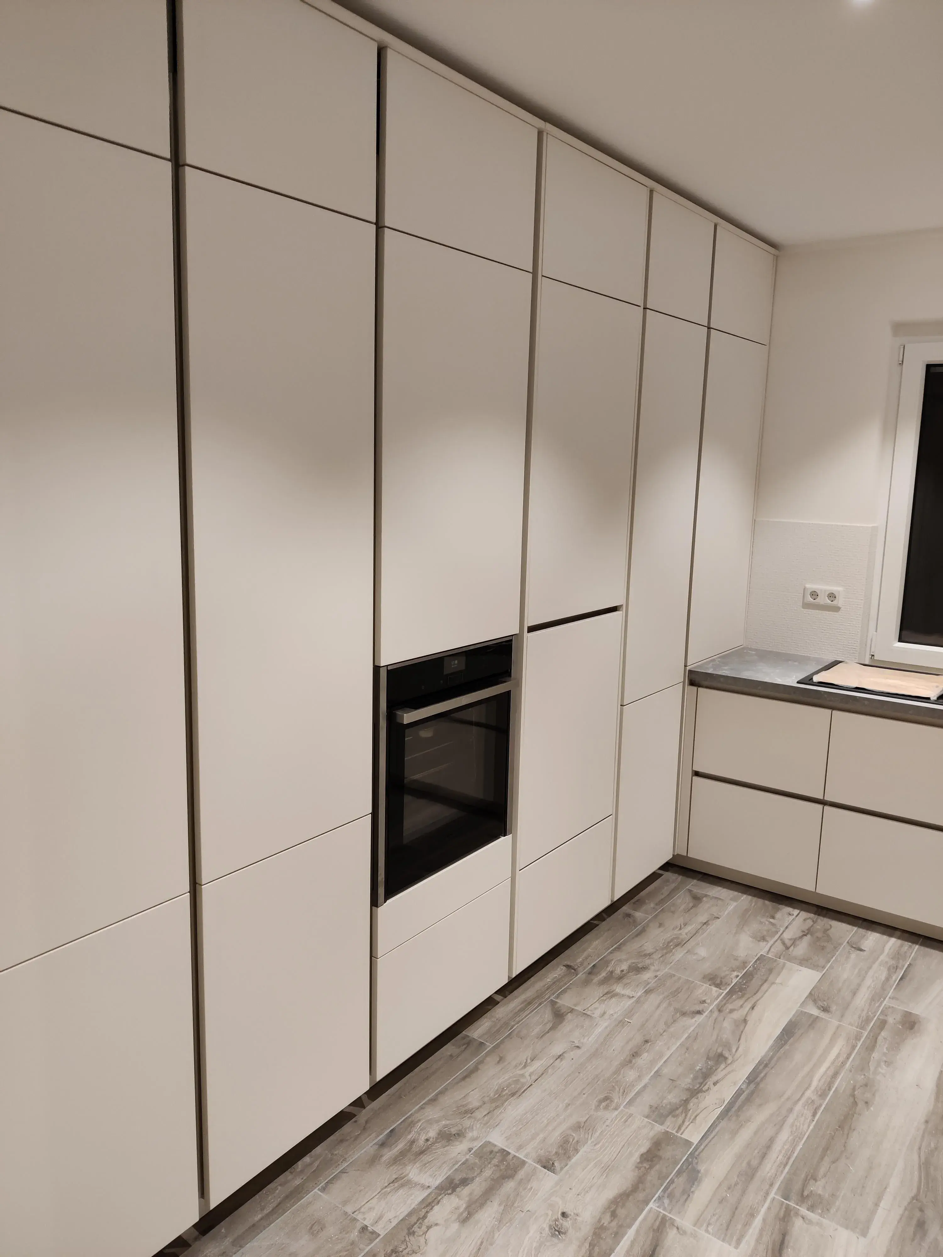 Moderne weiße Küche mit deckenhohen Hochschränken und integriertem Backofen