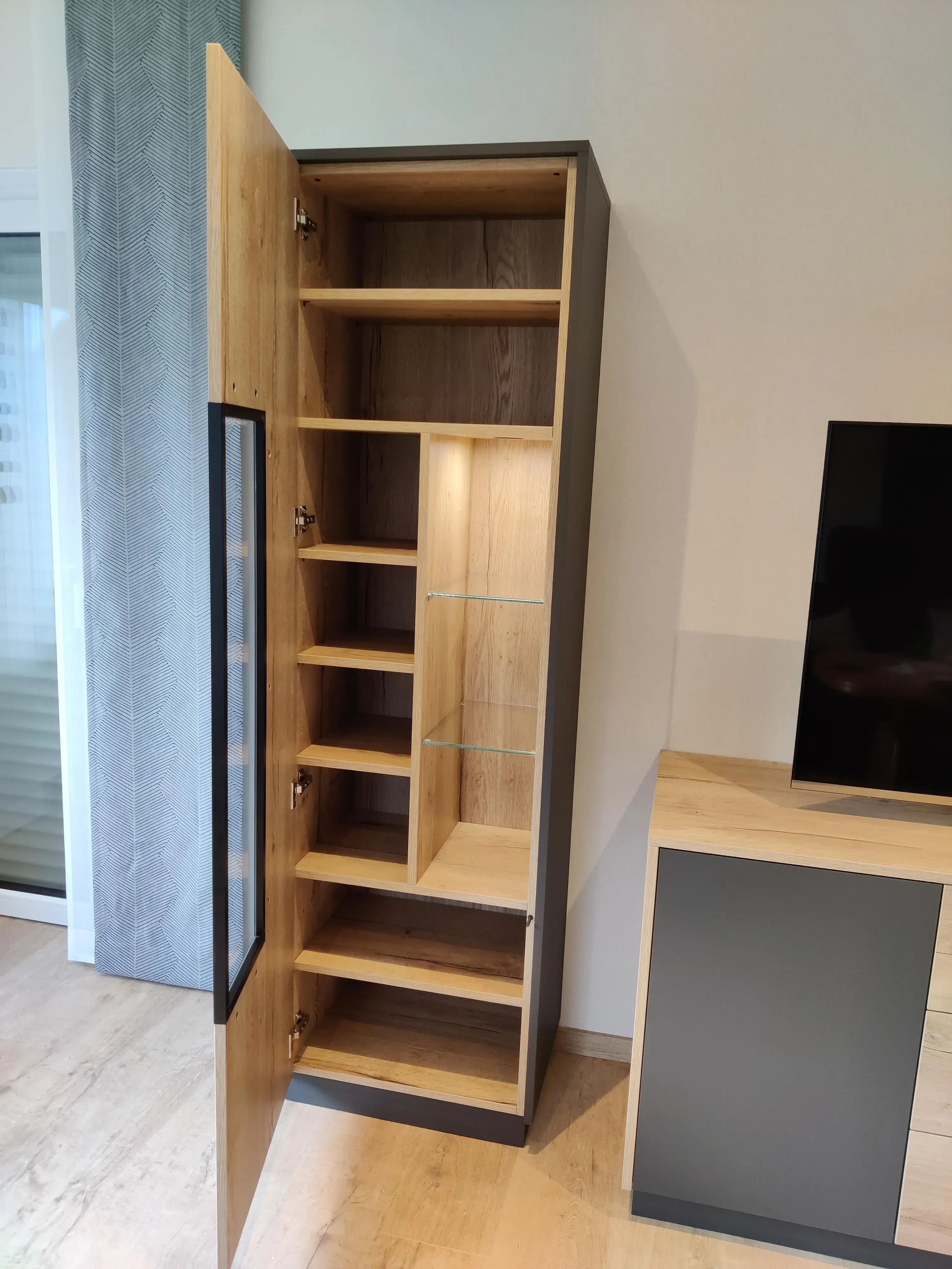 Geöffneter maßgefertigter Wohnzimmerschrank aus Holz mit Glasvitrine, Regalfächern und integriertem Stauraum