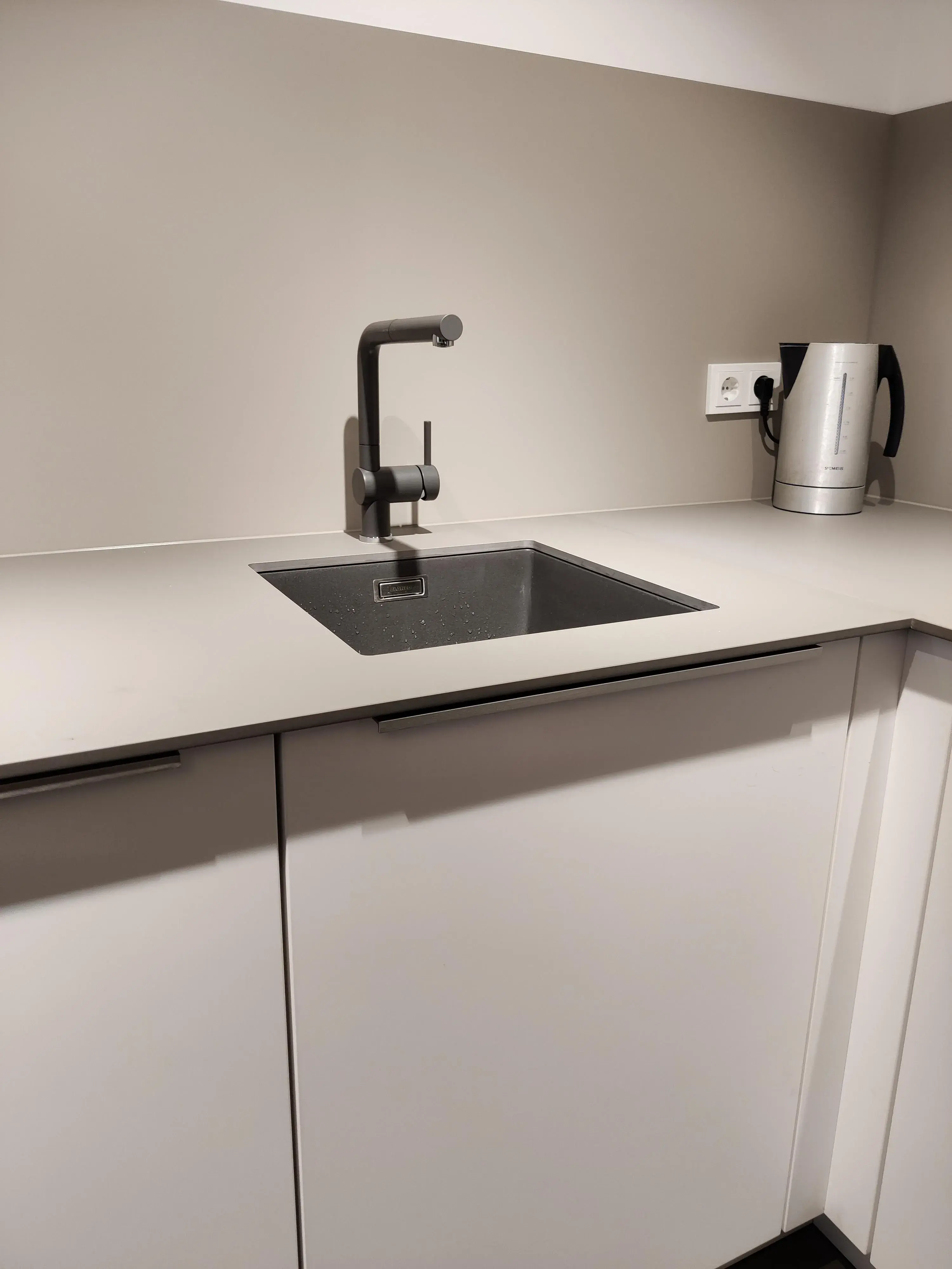 Moderne Küchenspüle mit schwarzem Spülbecken, schwarzer Armatur und heller Arbeitsplatte