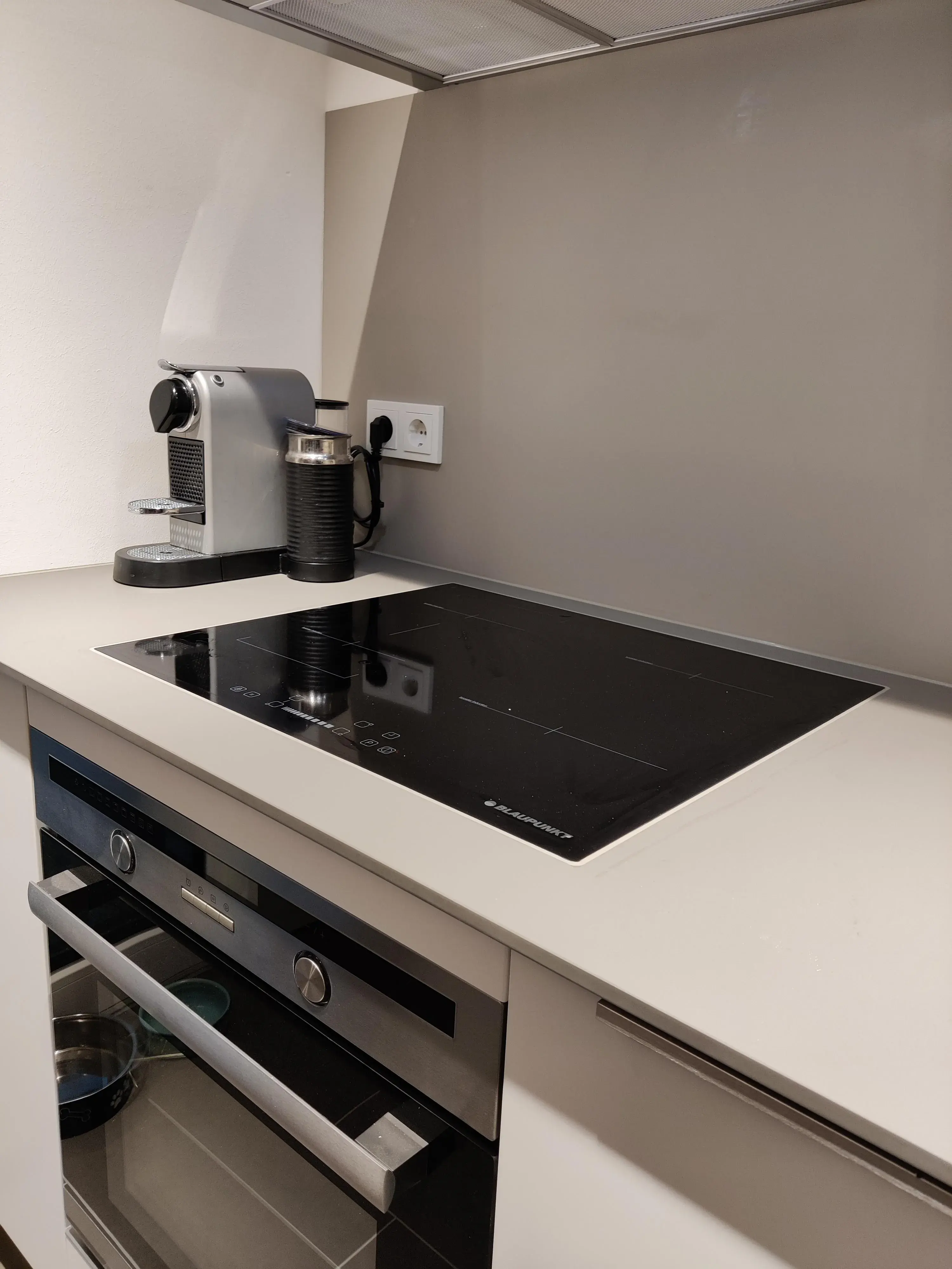 Modernes Induktionskochfeld mit Einbaubackofen und heller Arbeitsplatte
