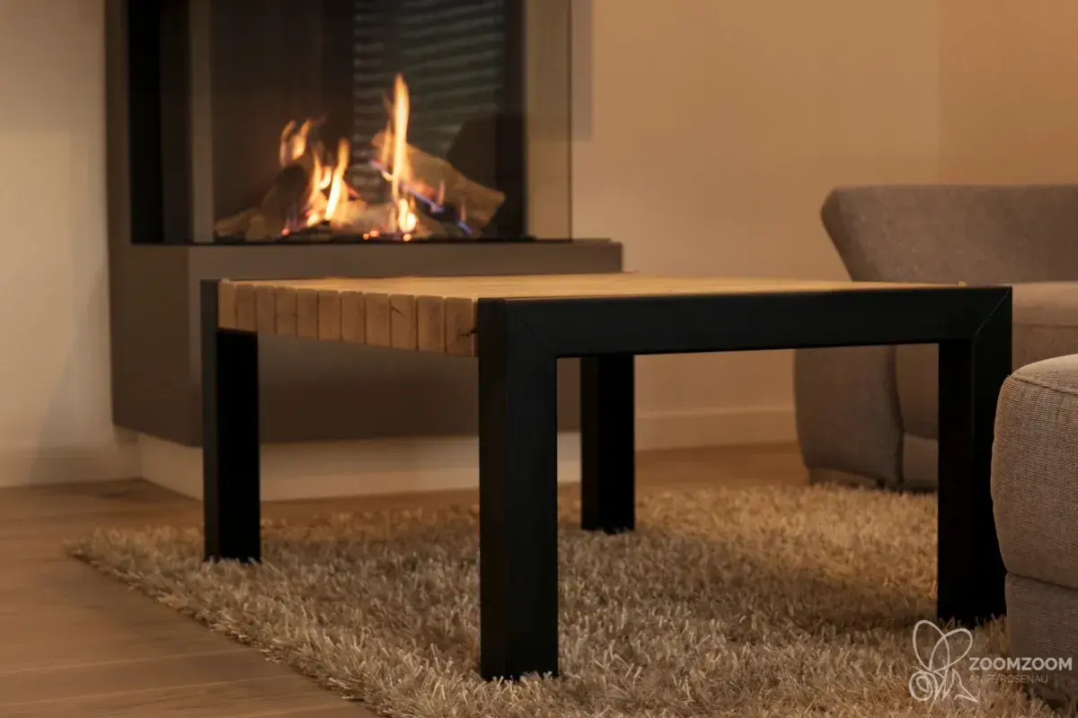 Individueller Couchtisch aus Massivholz mit schwarzem Metallgestell vor einem Kamin