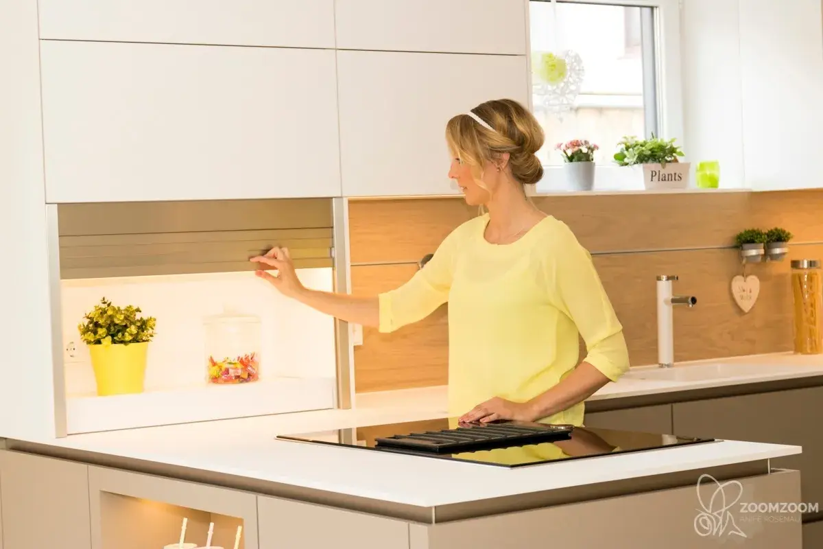 Moderne weiße Küche mit Kochinsel und geöffnetem Rollladenschrank für zusätzlichen Stauraum