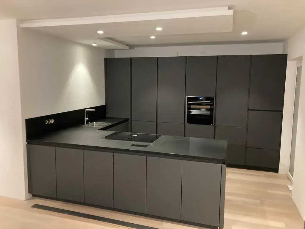 Moderne grifflose Küche in Anthrazit mit Kochinsel, dunkler Arbeitsplatte und deckenhoher Schrankwand